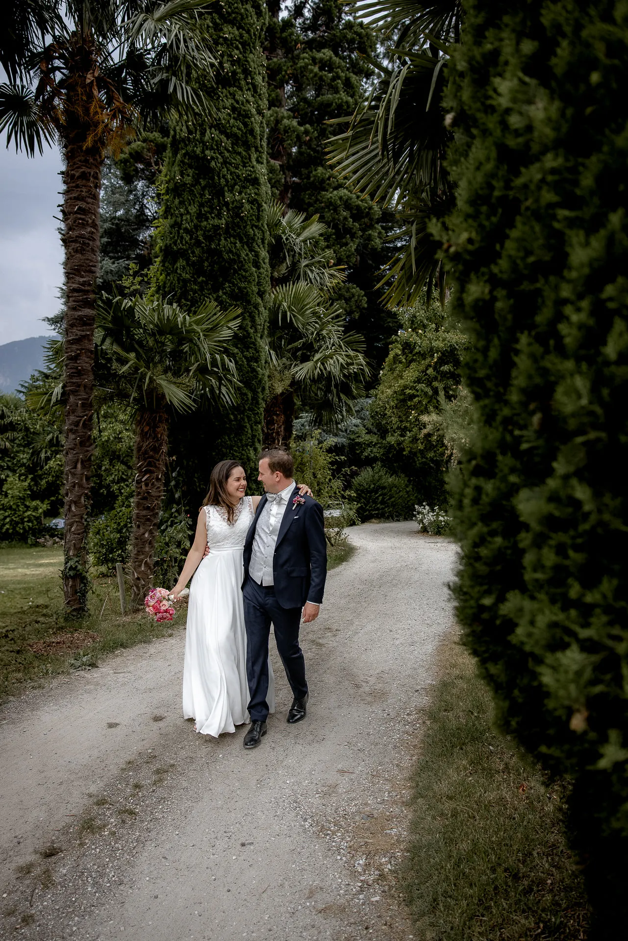 Wedding couple Ann-Kathrin and Tobias walks through palm garden at Italian wedding in Castel Pienzenau