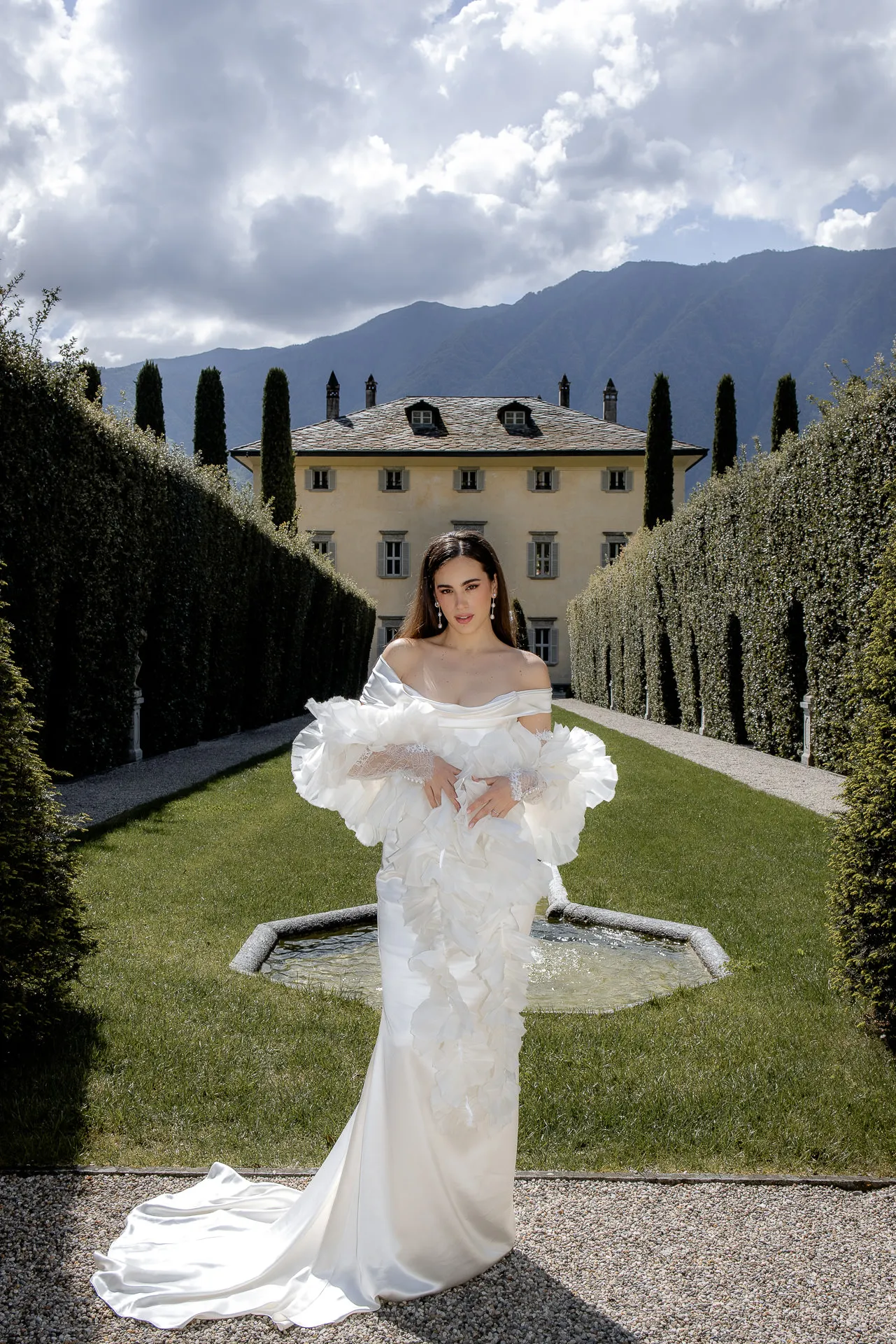 Bride in designer dress before Villa Balbiano Lake Como with mountain panorama