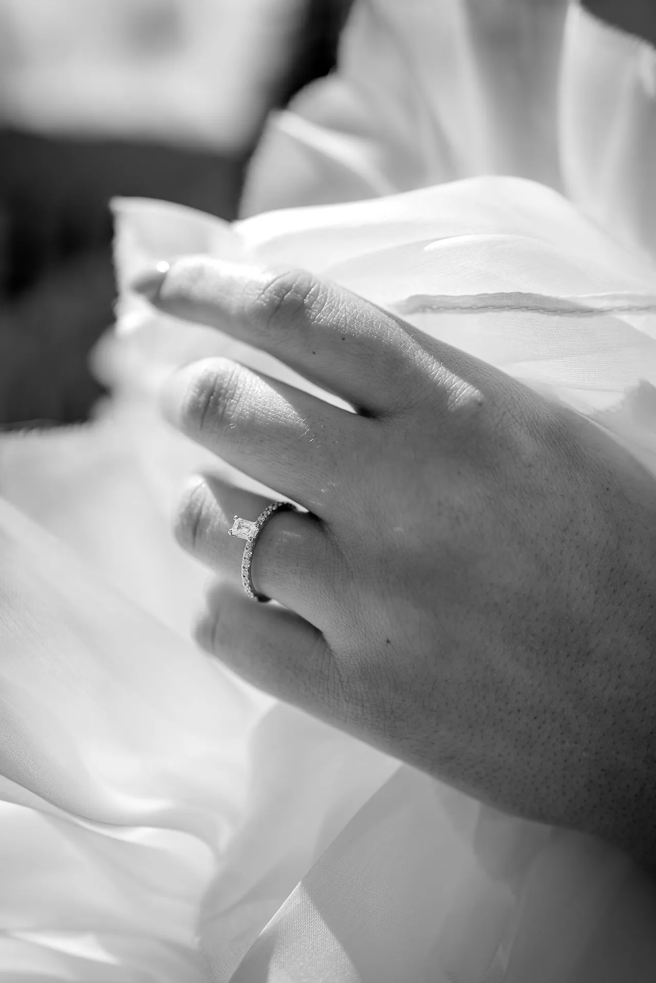 Detail shot of diamond engagement ring on bride's hand black and white