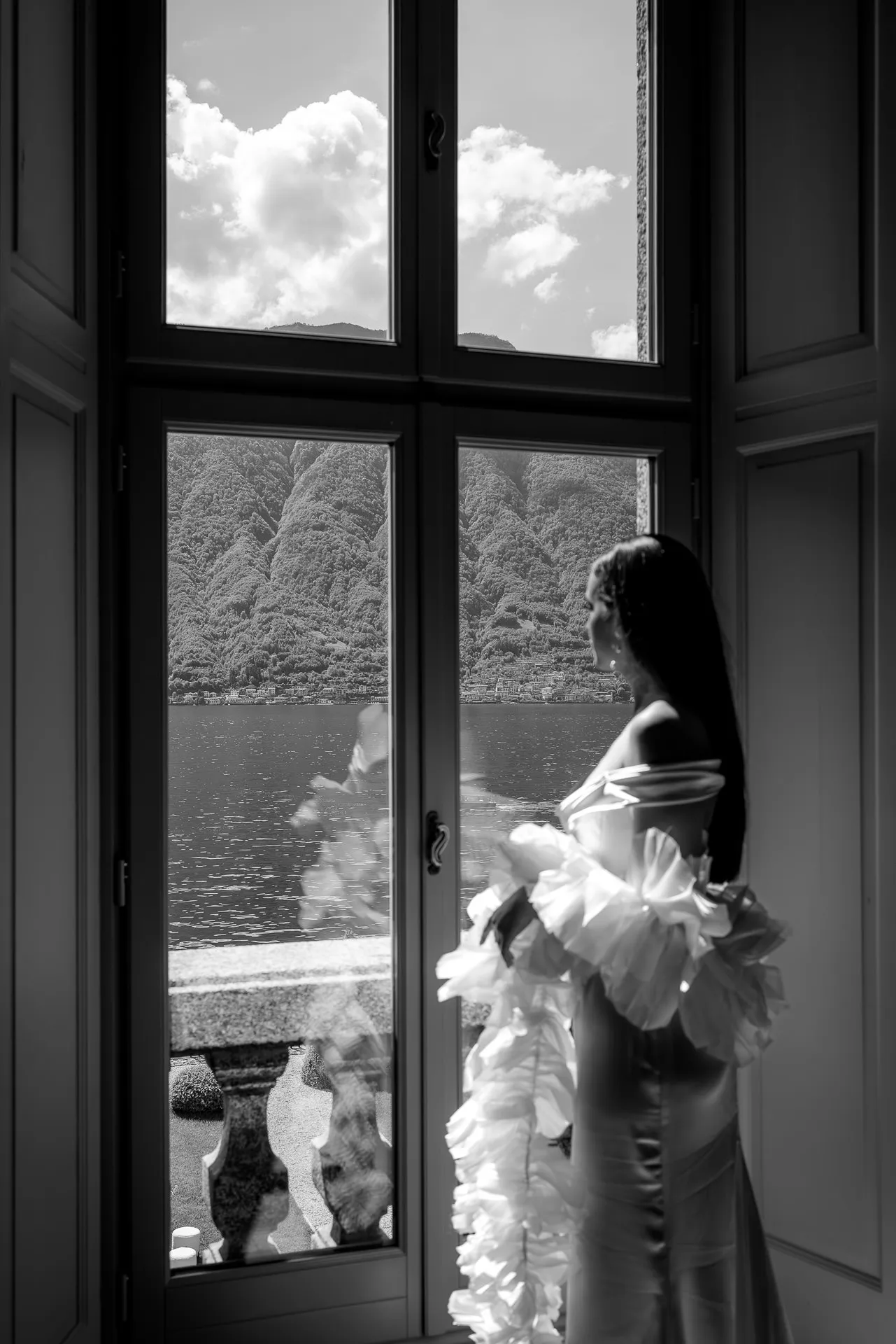 Bride looking out window at Lake Como with mountains black and white