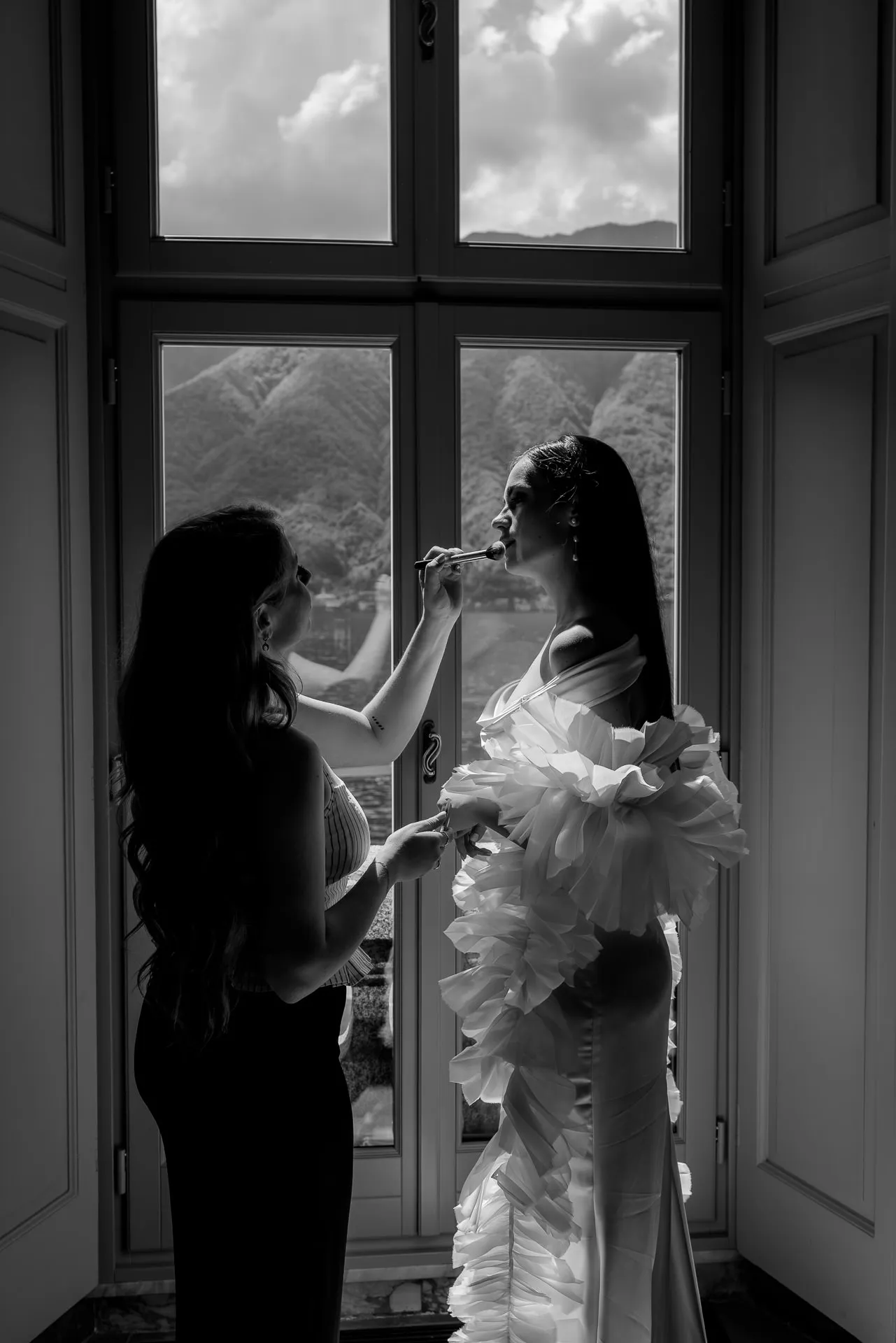 Bride getting makeup applied with lake view black and white
