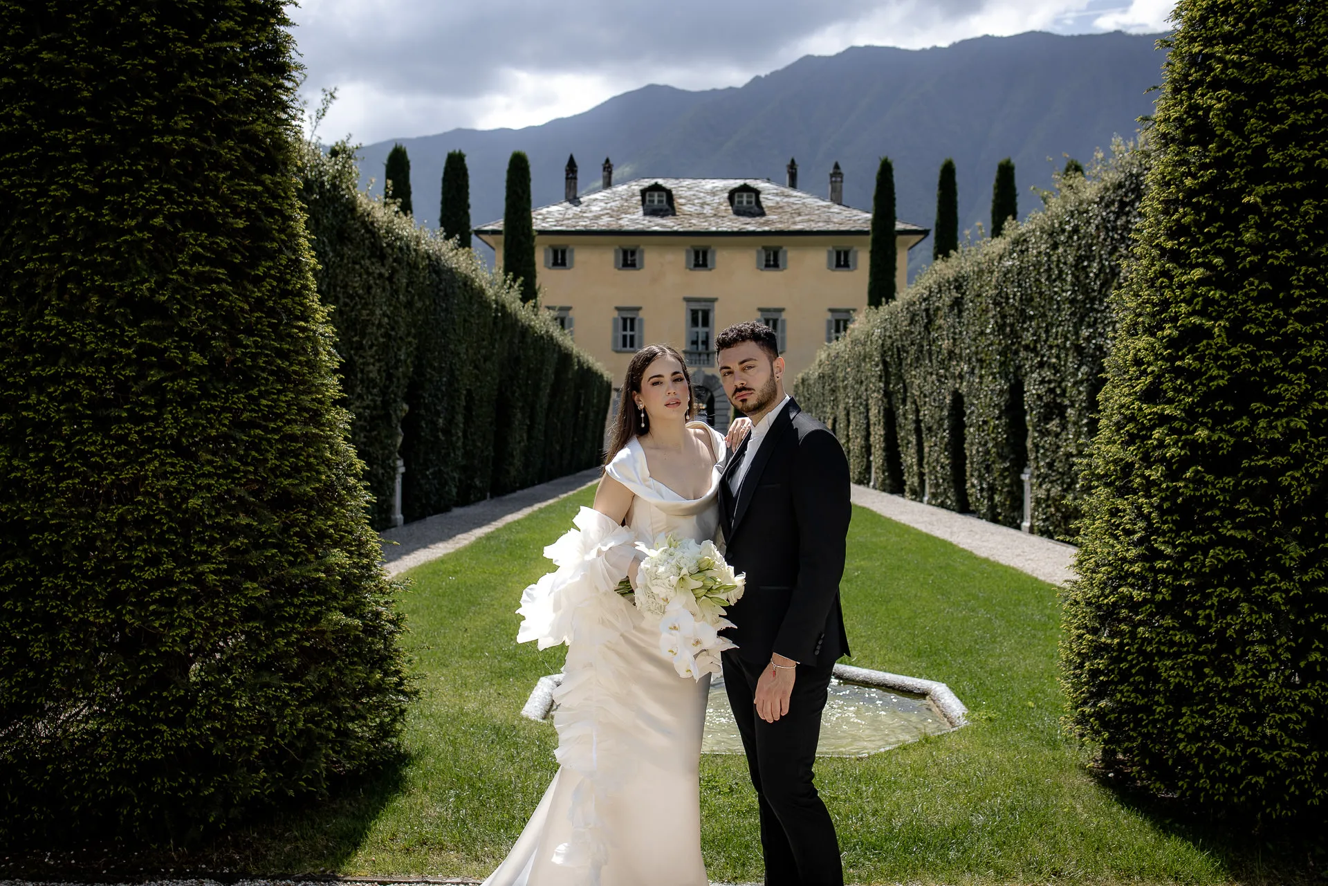 Wedding couple before Villa Balbiano with dramatic mountain backdrop at Lake Como