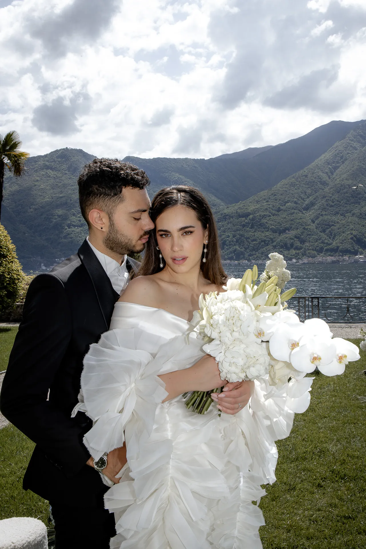 Romantic wedding couple with orchid bouquet at Lake Como before mountains