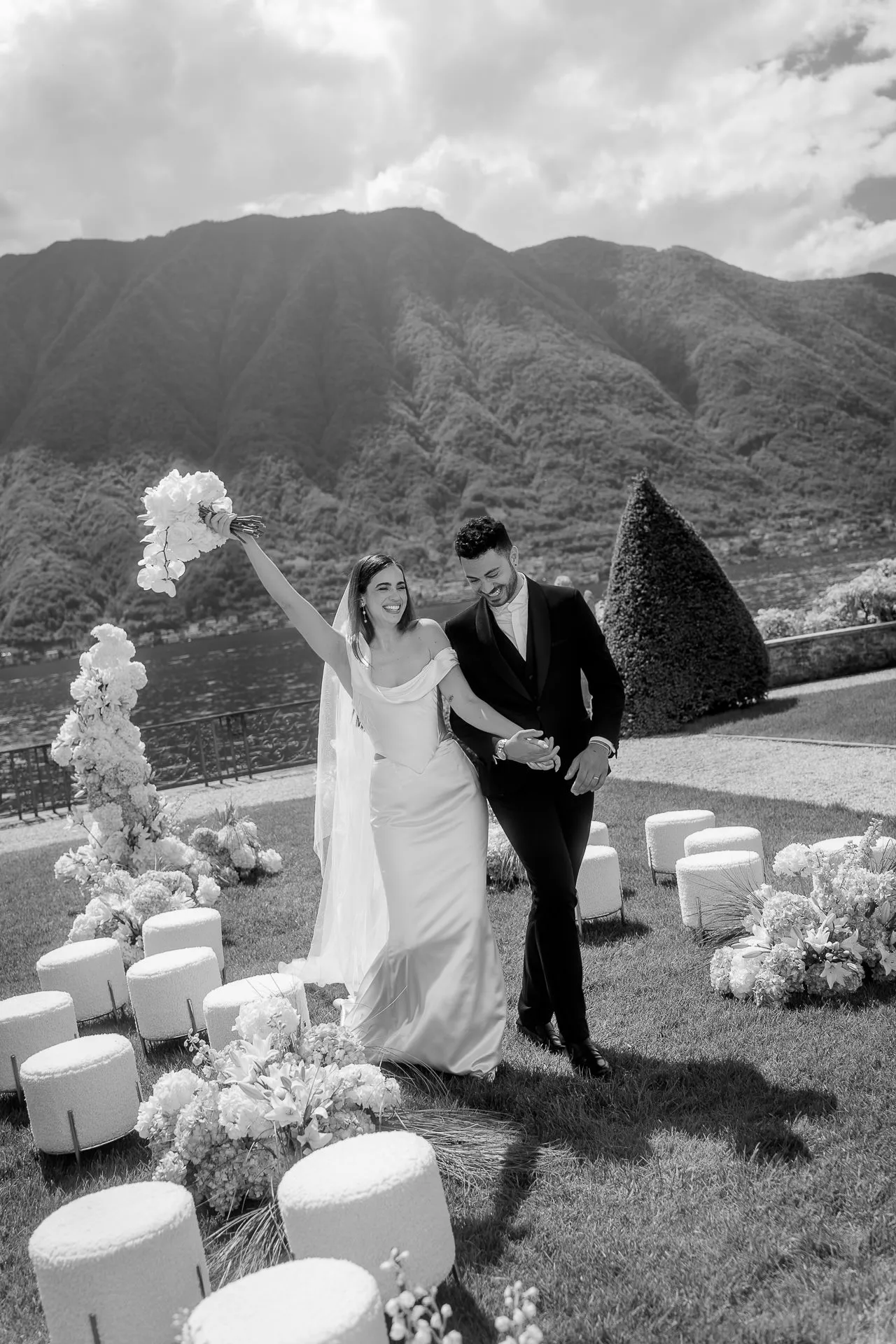 Newlywed couple walking through ceremony aisle at Lake Como black and white