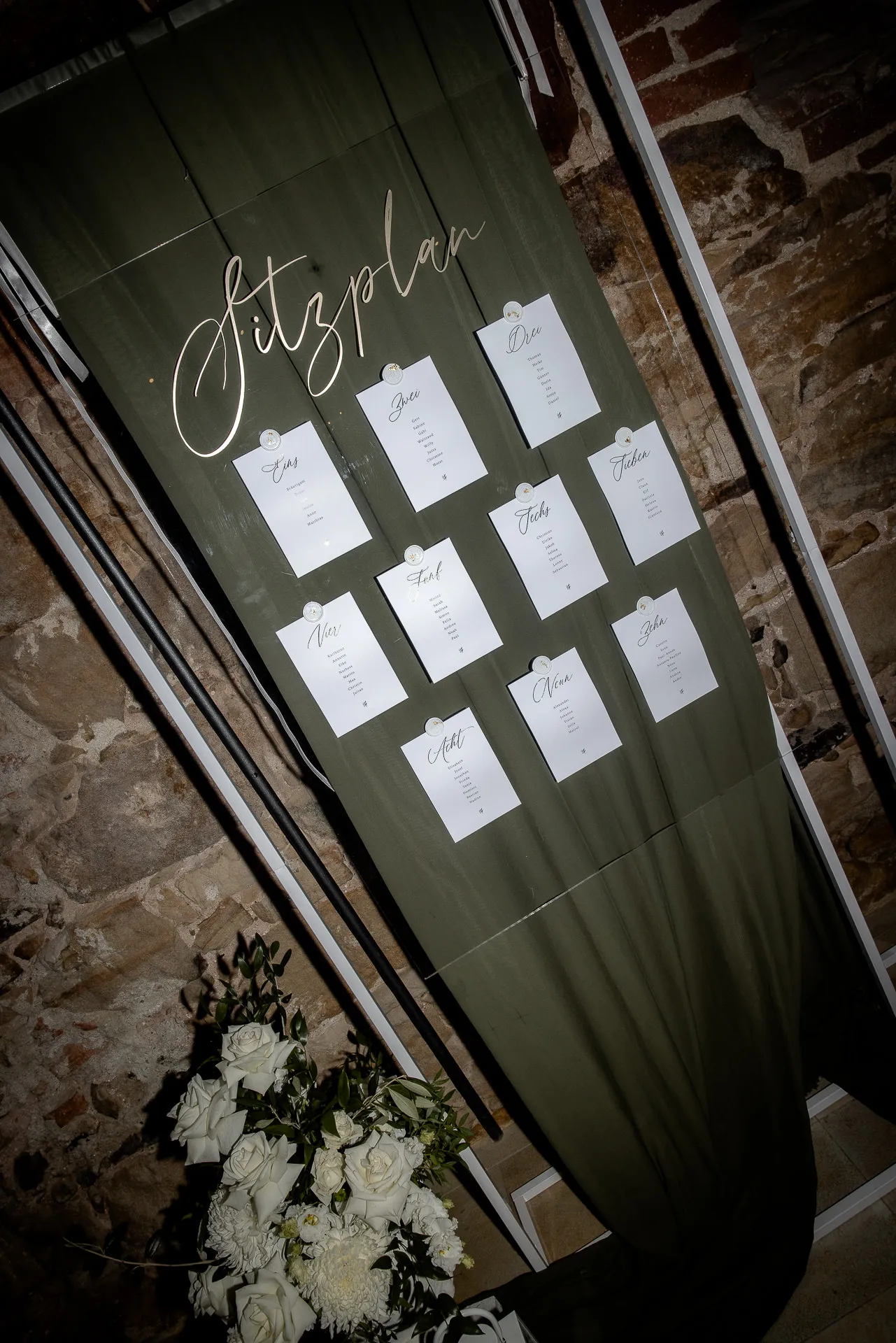Stylish seating chart with calligraphy and white bridal bouquet at Schloss Eyrichshof wedding