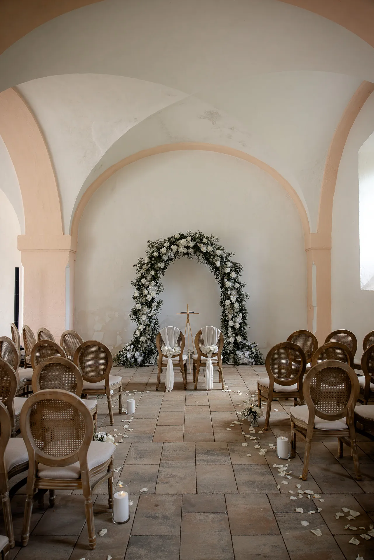 Romantic wedding ceremony with flower arch in historic vault at Schloss Eyrichshof