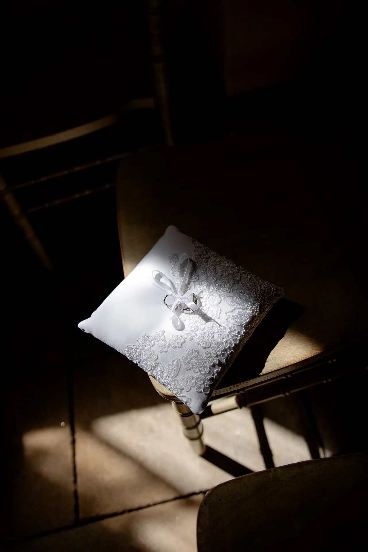 Elegant ring pillow with lace and satin ribbon in dramatic light