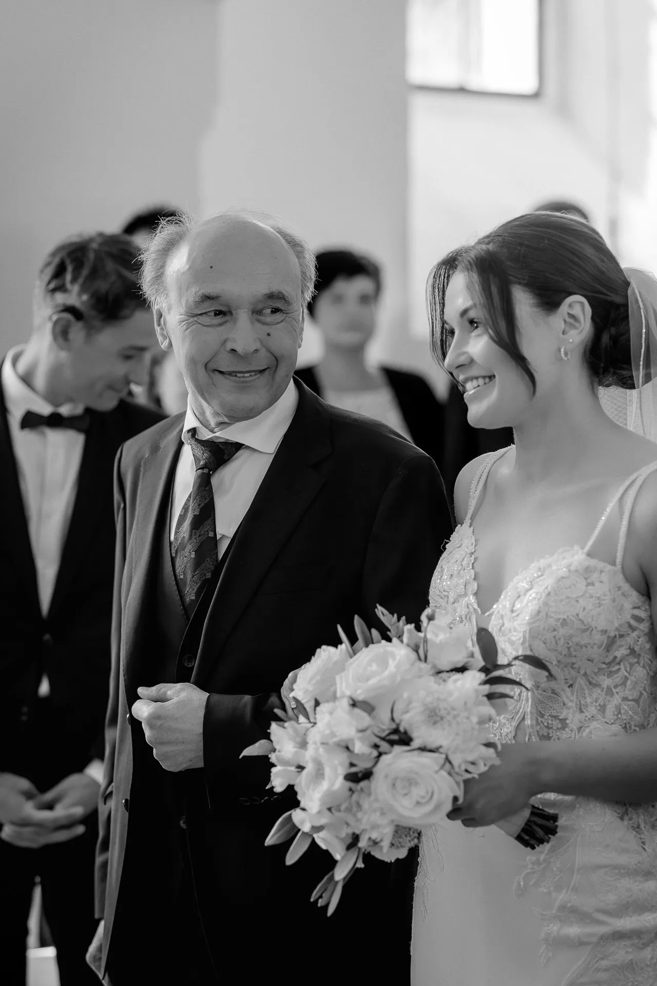 Happy bride with father entering ceremony at Schloss Eyrichshof in black and white
