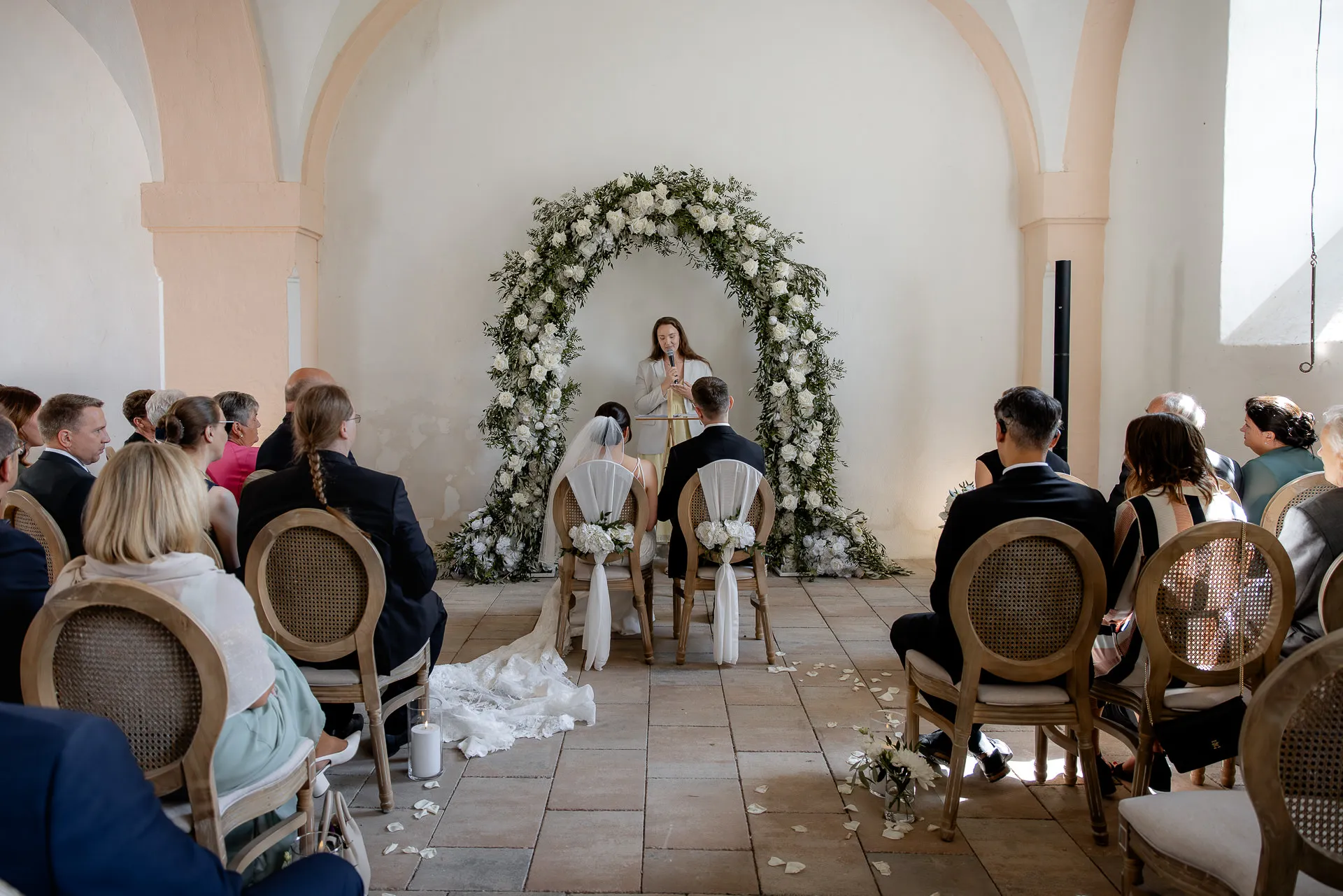 Free wedding ceremony with flower arch in historic vault at Schloss Eyrichshof with wedding party