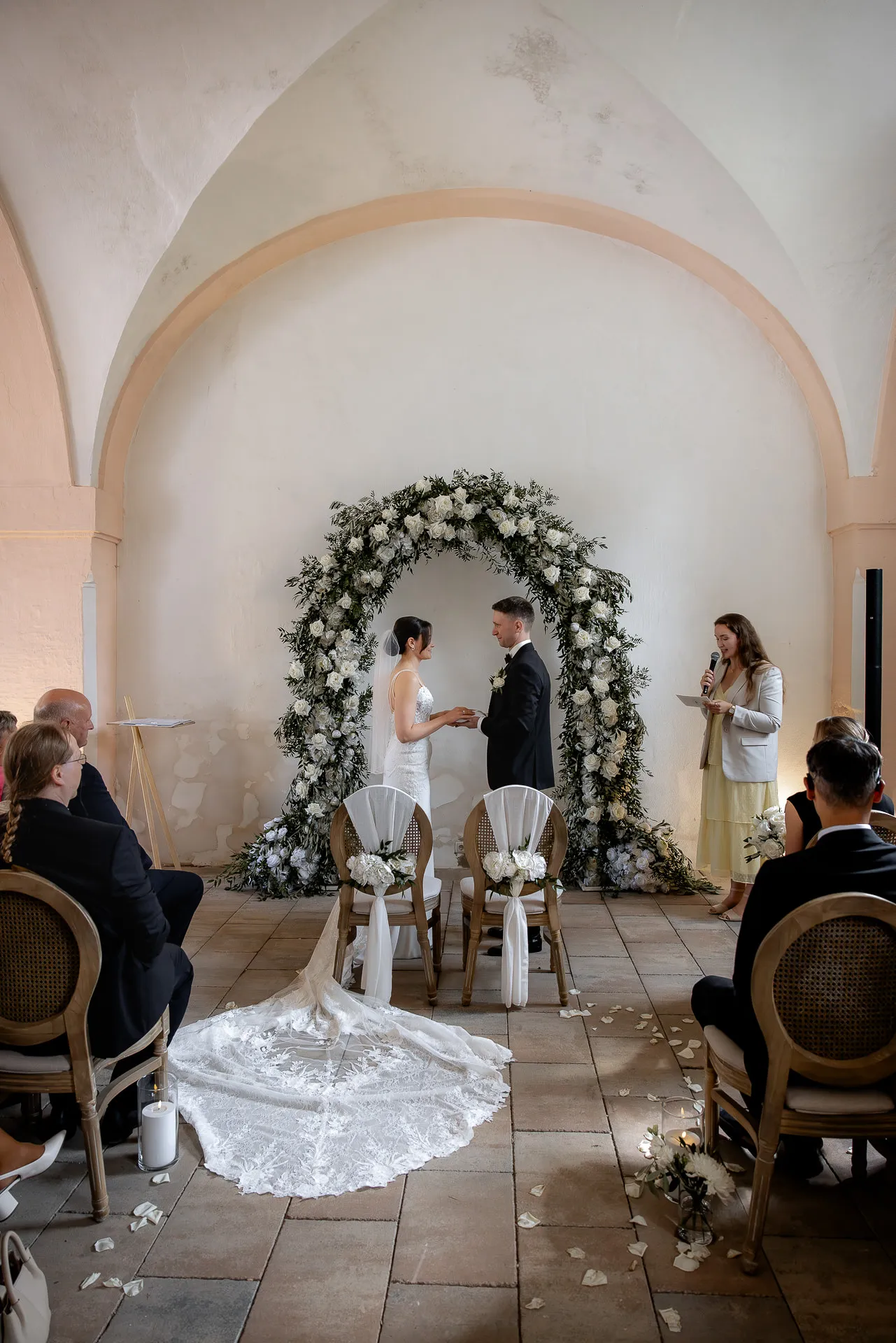 Ring exchange at free ceremony before flower arch in vault at Schloss Eyrichshof
