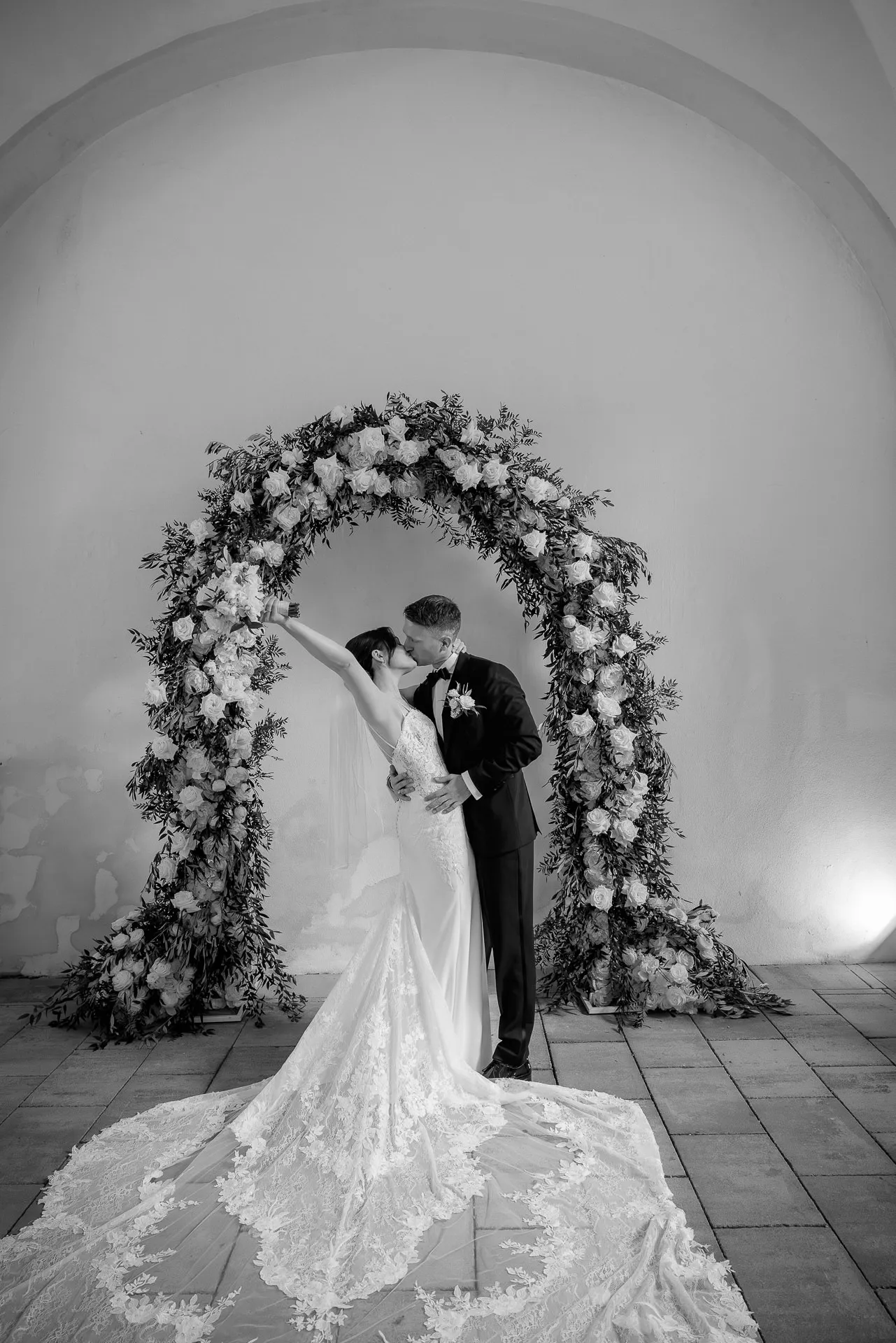 Romantic kiss under flower arch at castle wedding Eyrichshof in black and white
