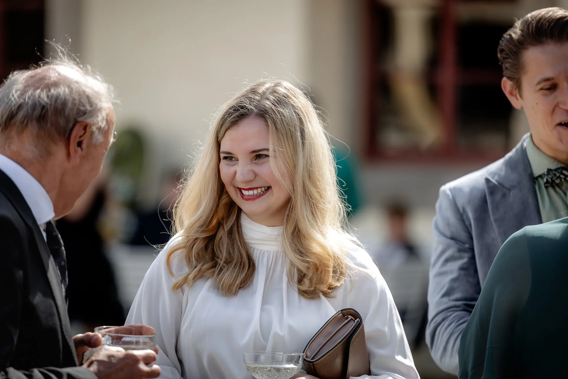 Laughing wedding guests at champagne reception at Schloss Eyrichshof in sunshine