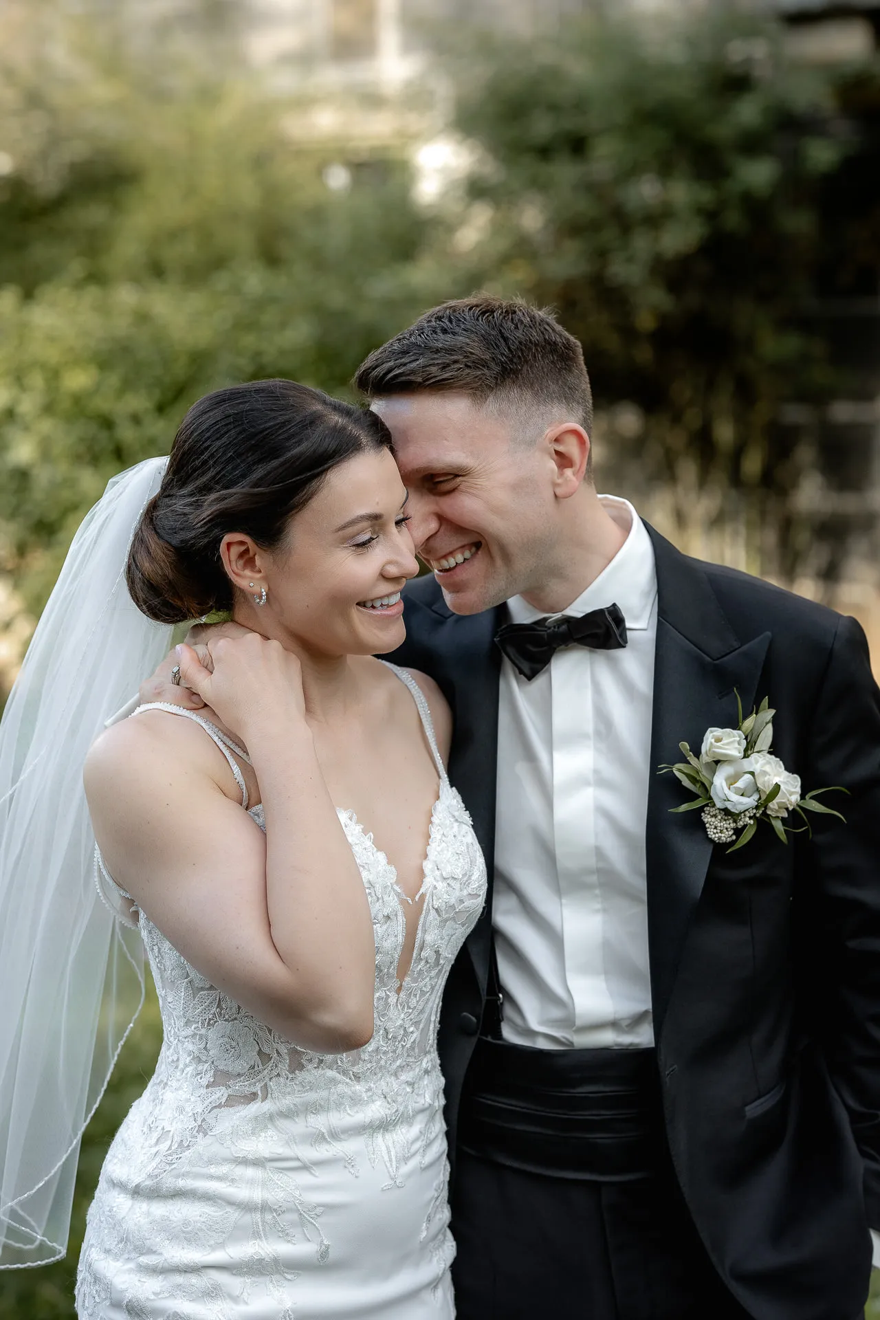 Happy bride and groom in front of Schloss Eyrichshof with white boutonniere and veil