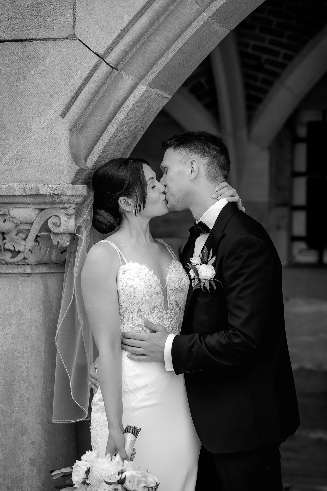 Romantic kiss between bride and groom at Schloss Eyrichshof with bouquet in black and white