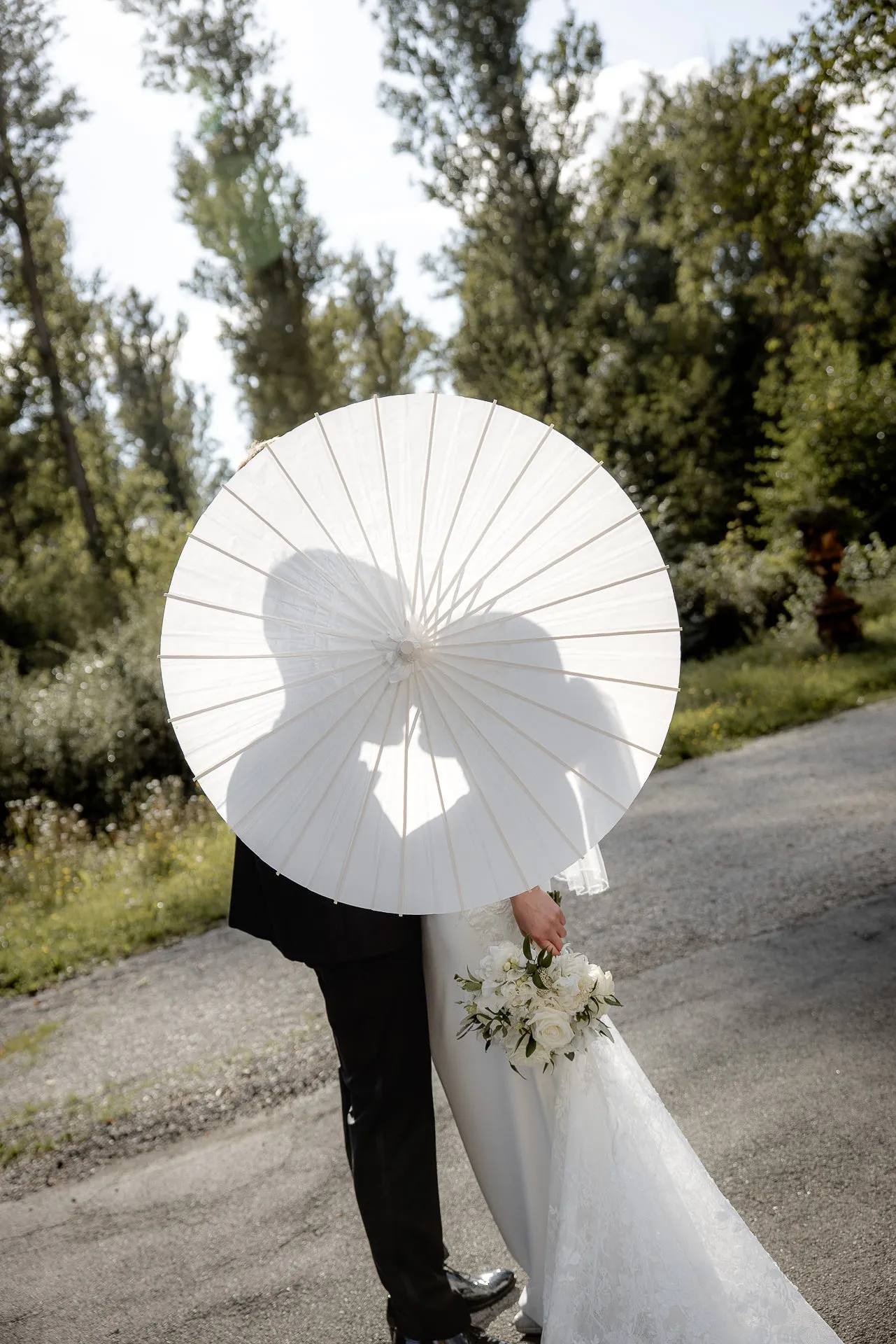 Creative wedding photo with white parasol and bridal bouquet at Schloss Eyrichshof