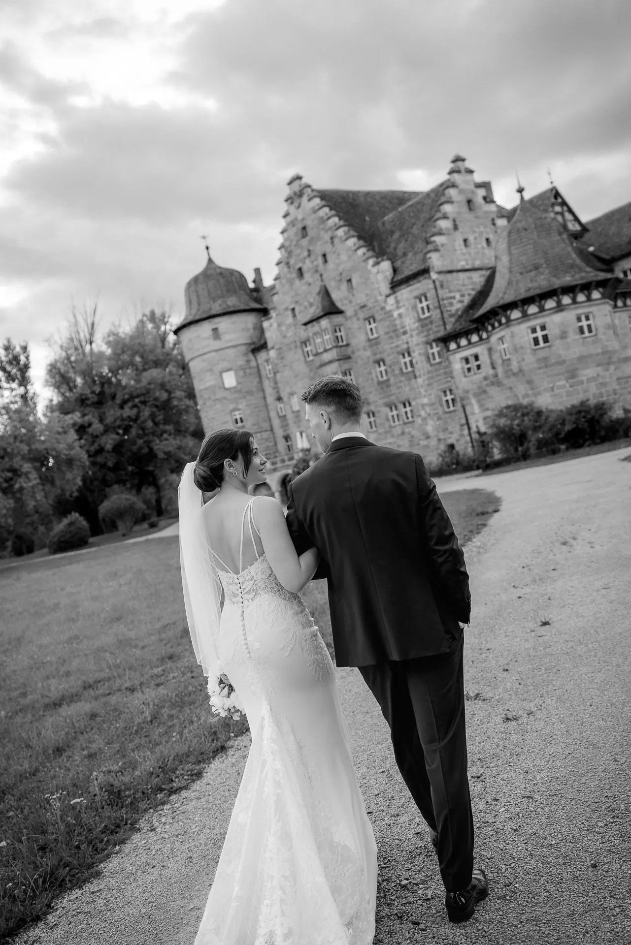 Bride and groom walking in front of Schloss Eyrichshof scenery at evening wedding in black and white