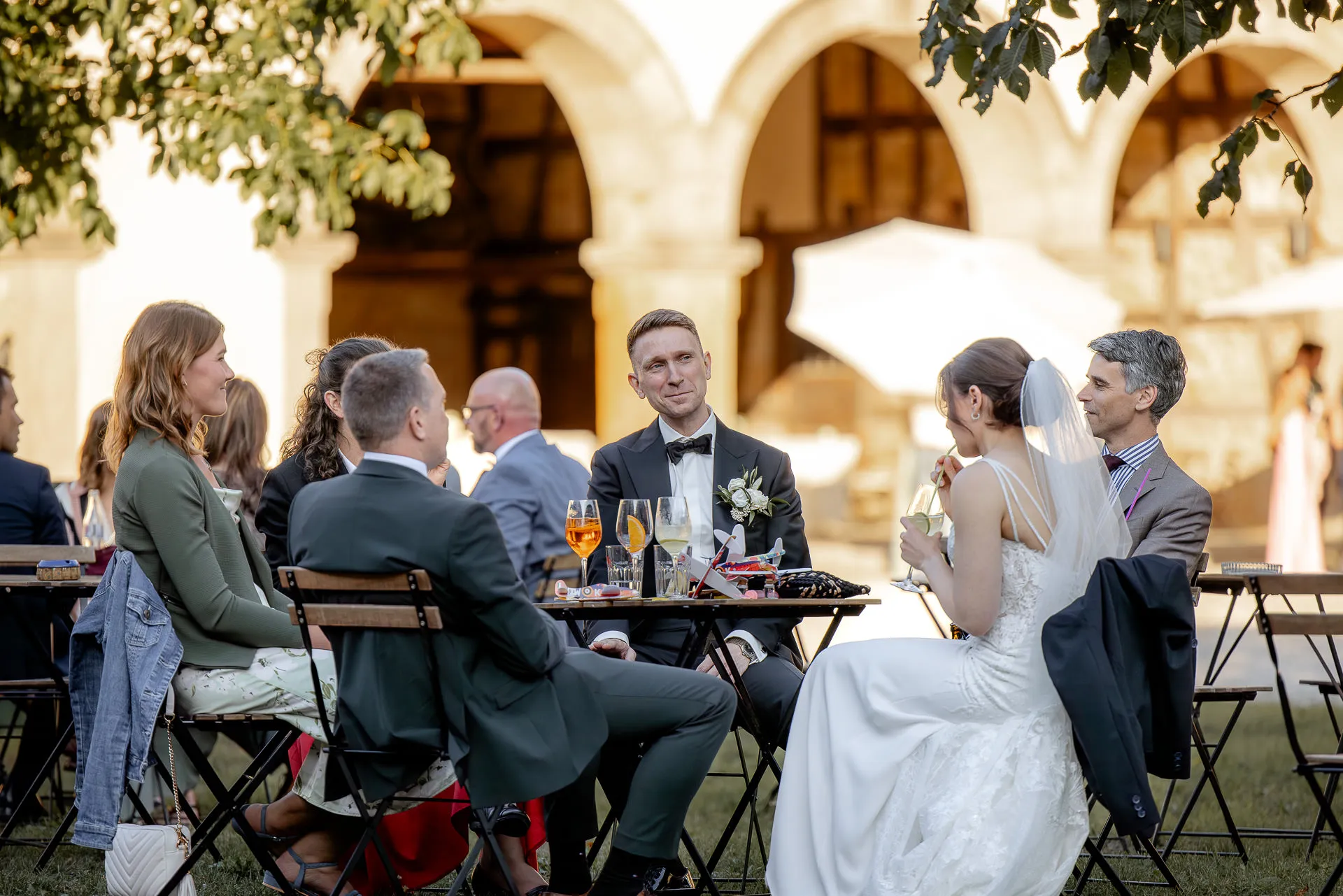 Convivial wedding celebration with guests at table at Schloss Eyrichshof in evening light