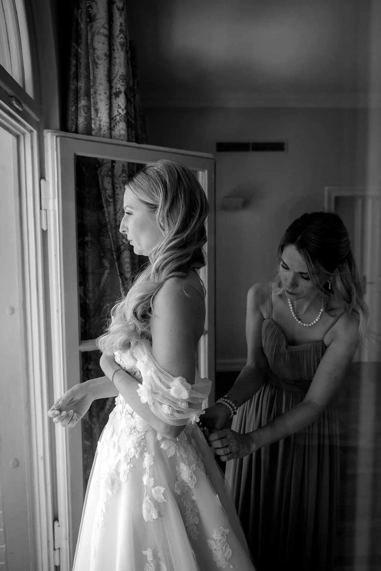 Emotional bride getting dressed with bridesmaid at luxury La Villa wedding