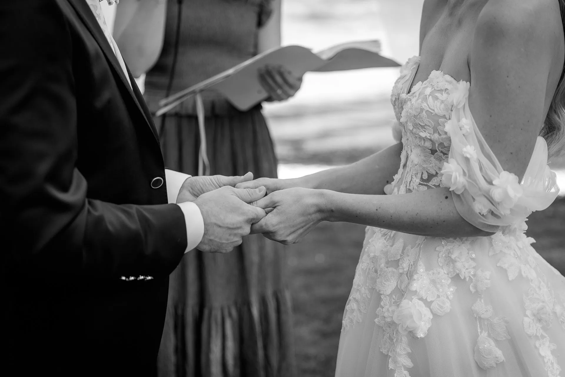 Detail shot holding hands during ceremony black and white