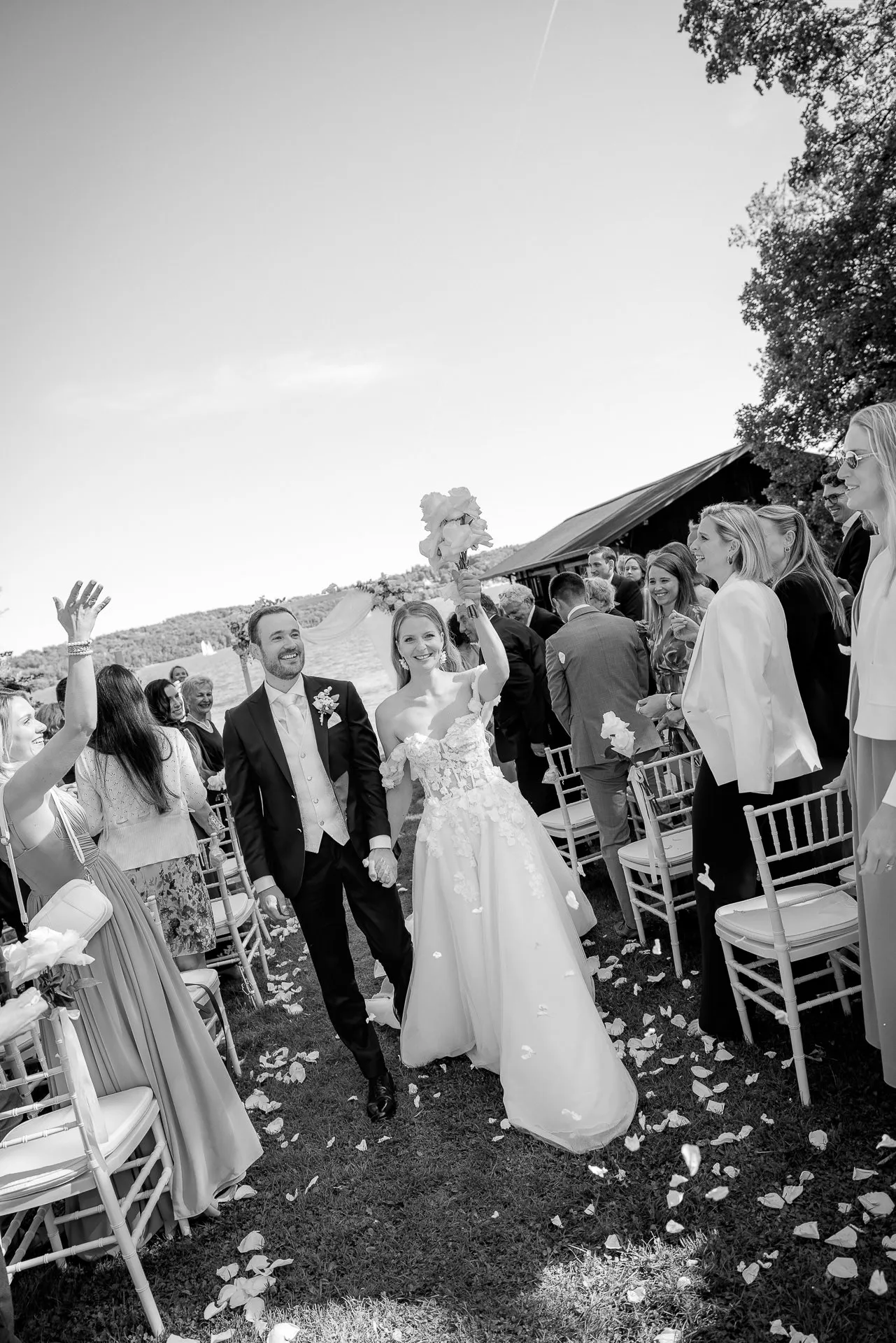Cheering couple exiting after ceremony with wedding guests