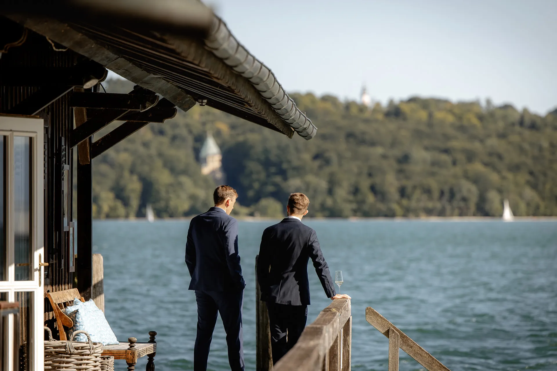 Two grooms with champagne glasses at boathouse Lake Starnberg