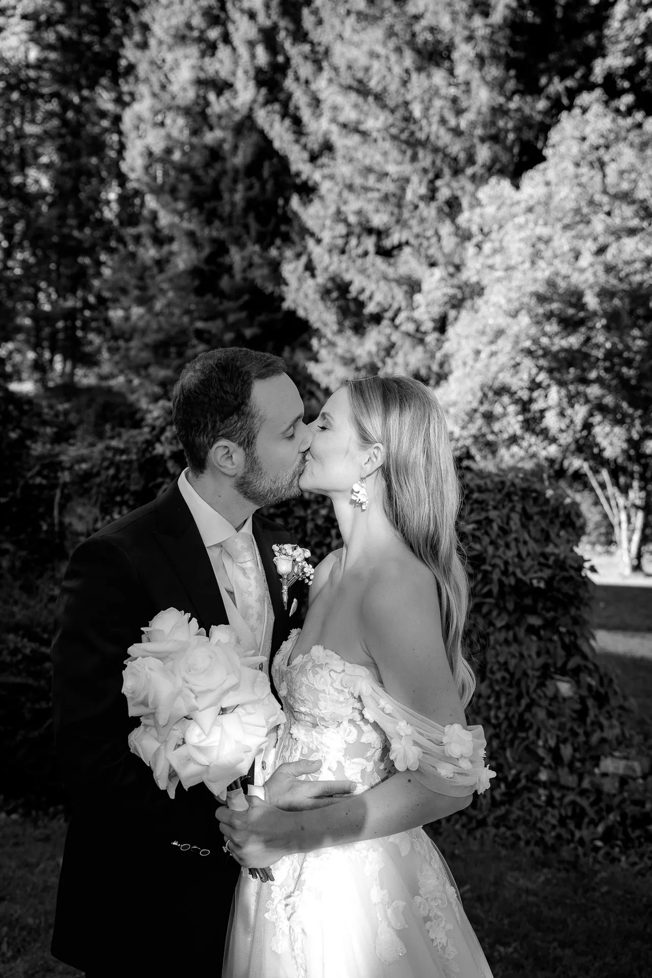 Romantic kiss of couple with bridal bouquet black and white