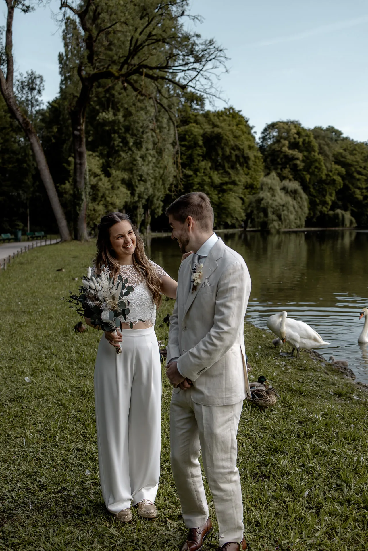 First Look in Englischer Garten Munich – bride and groom with swans by the lake