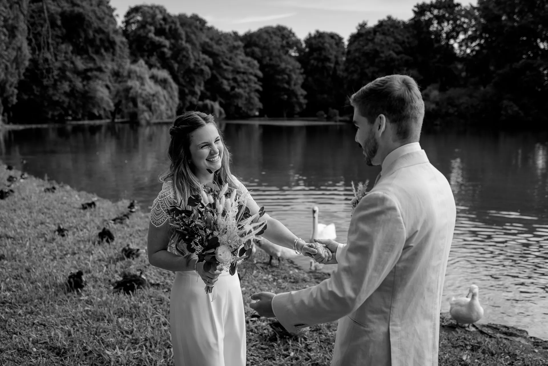 Emotional First Look in Englischer Garten – bride and groom by the lake in black and white