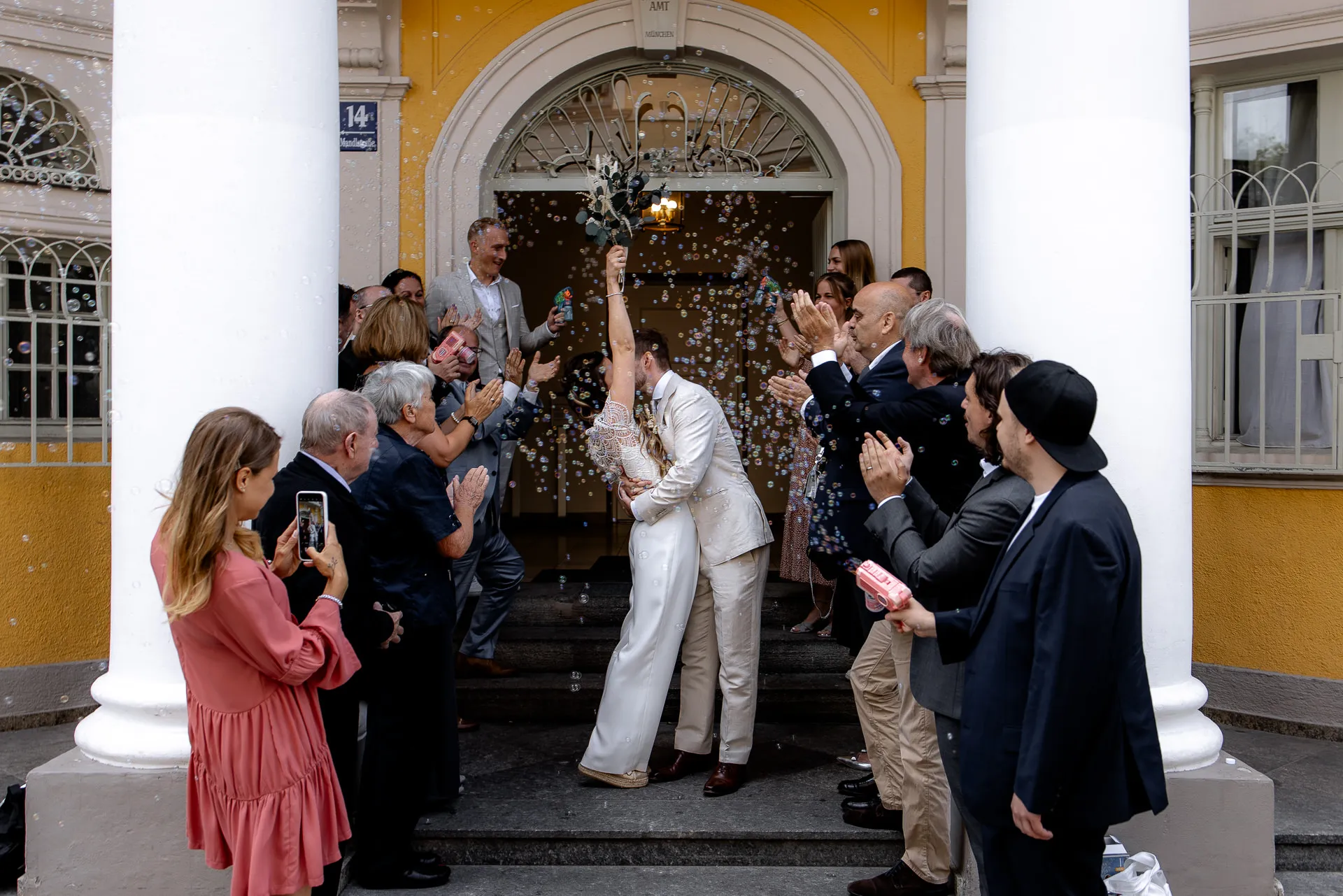 Bride and groom with bubbles in front of Standesamt Mandlstraße Munich