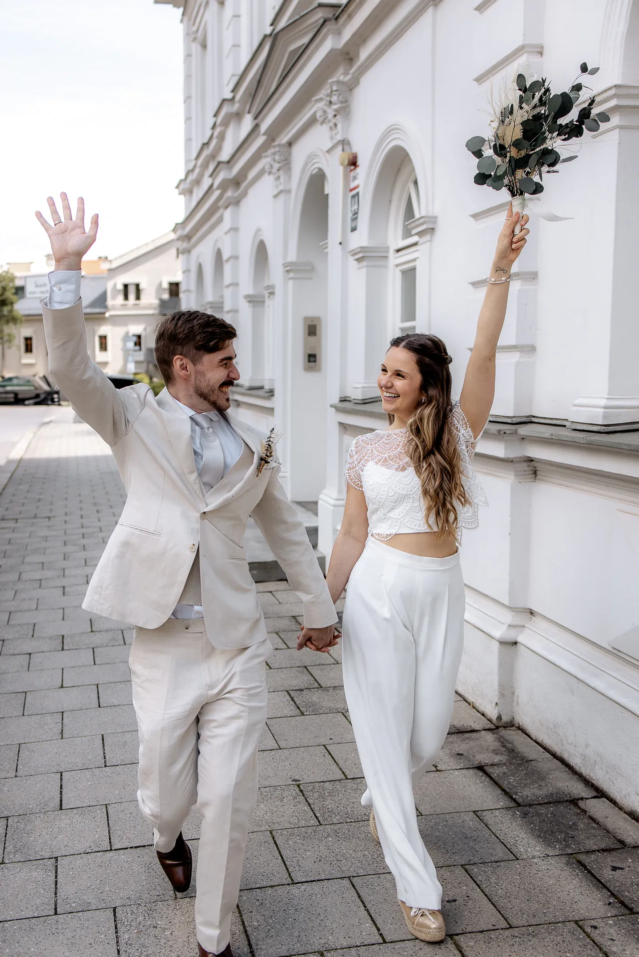 Cheering bride and groom in front of Standesamt Munich – authentic wedding photography