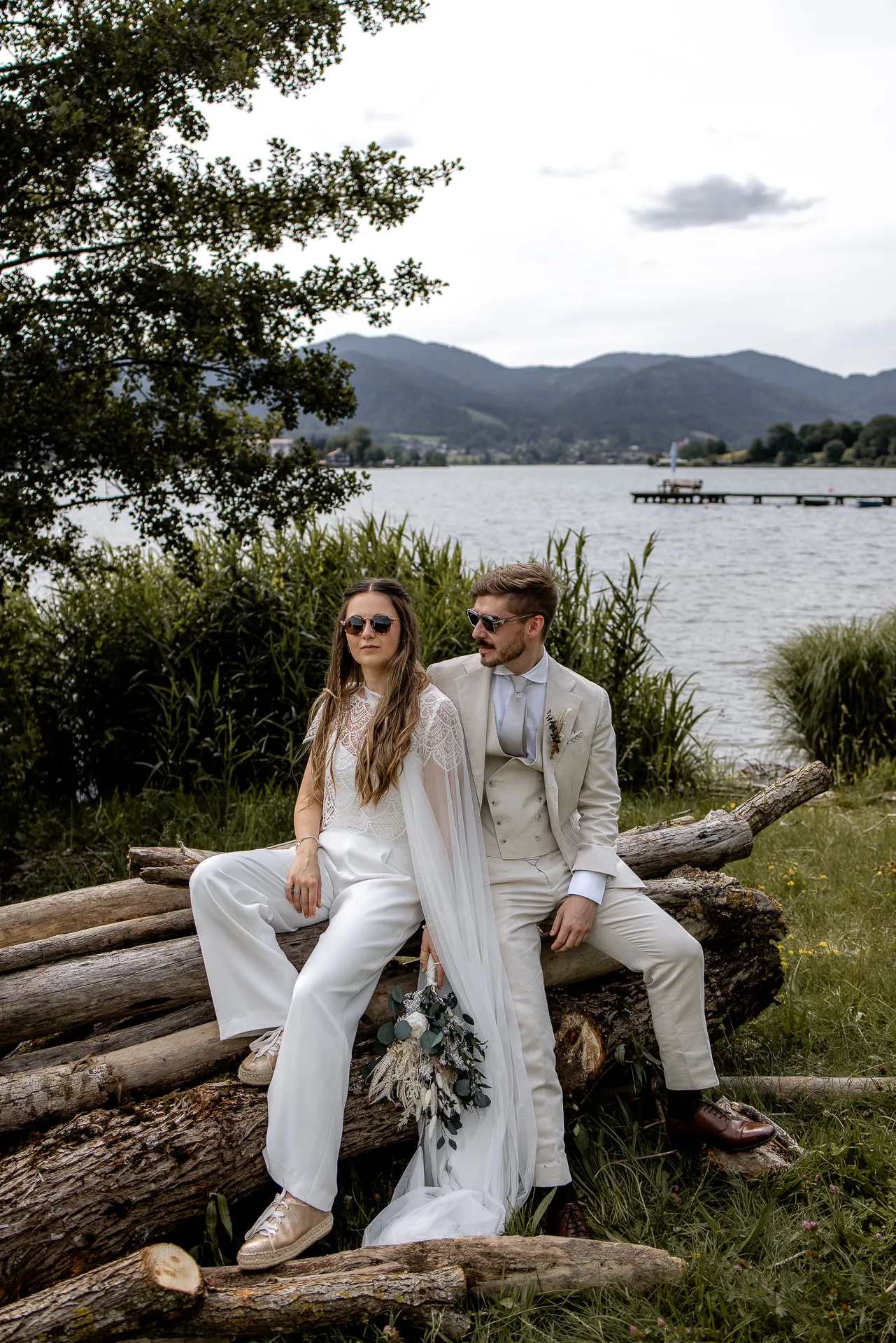 Relaxed couple at Lake Tegernsee shore with sunglasses – natural wedding photography