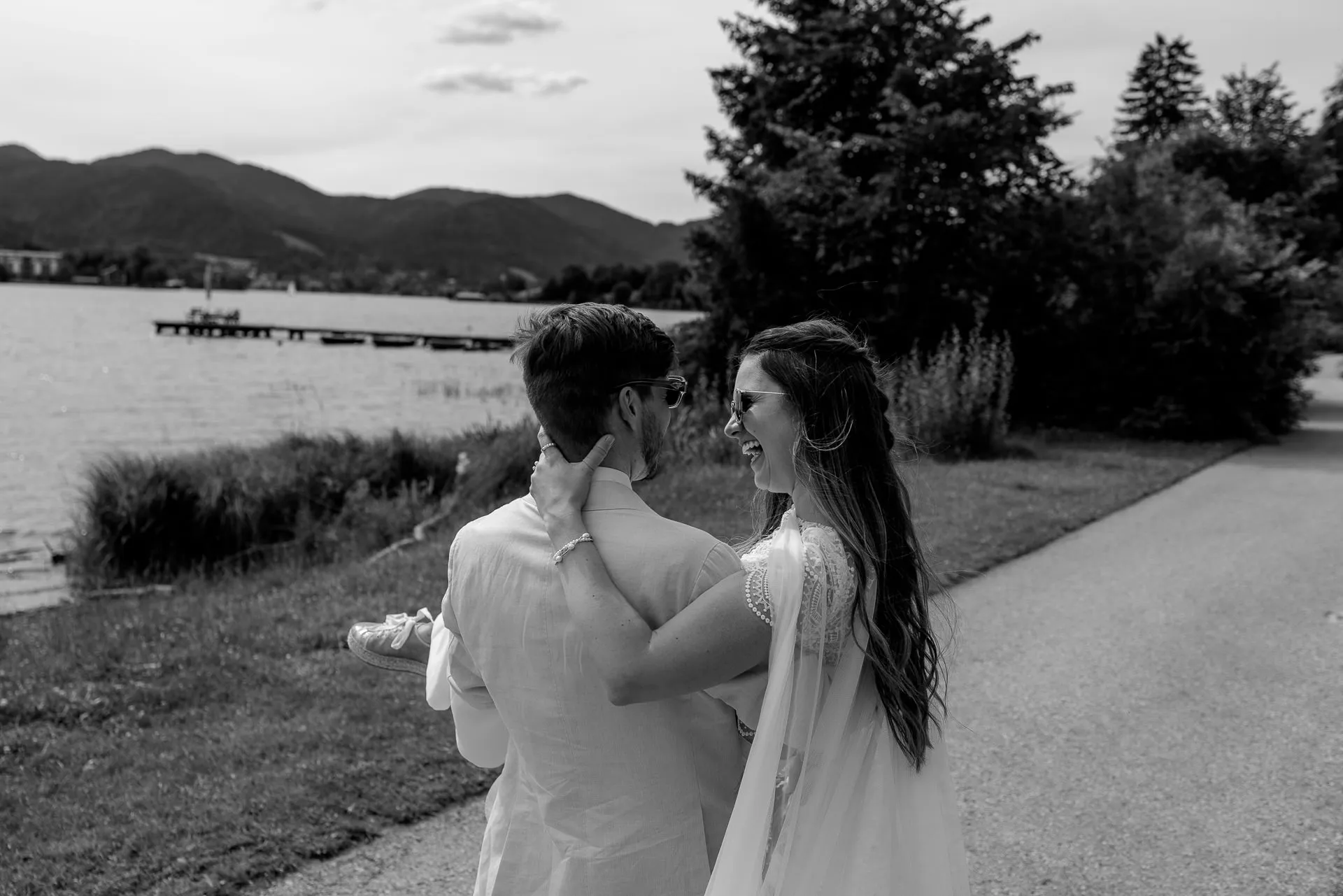 Couple walk along Lake Tegernsee shore in black and white – romantic wedding photography