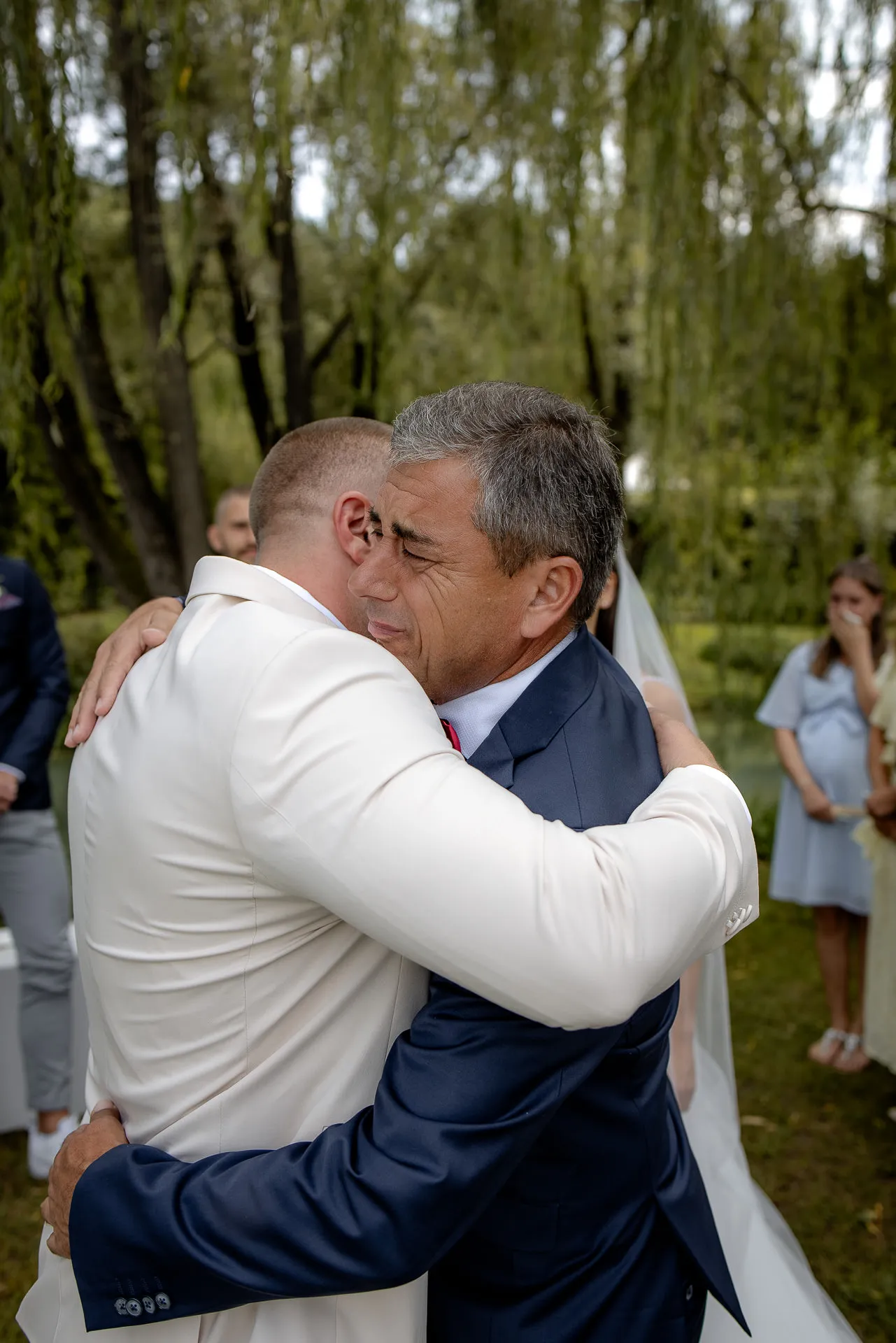 Heartfelt embrace between groom and father at Italian wedding