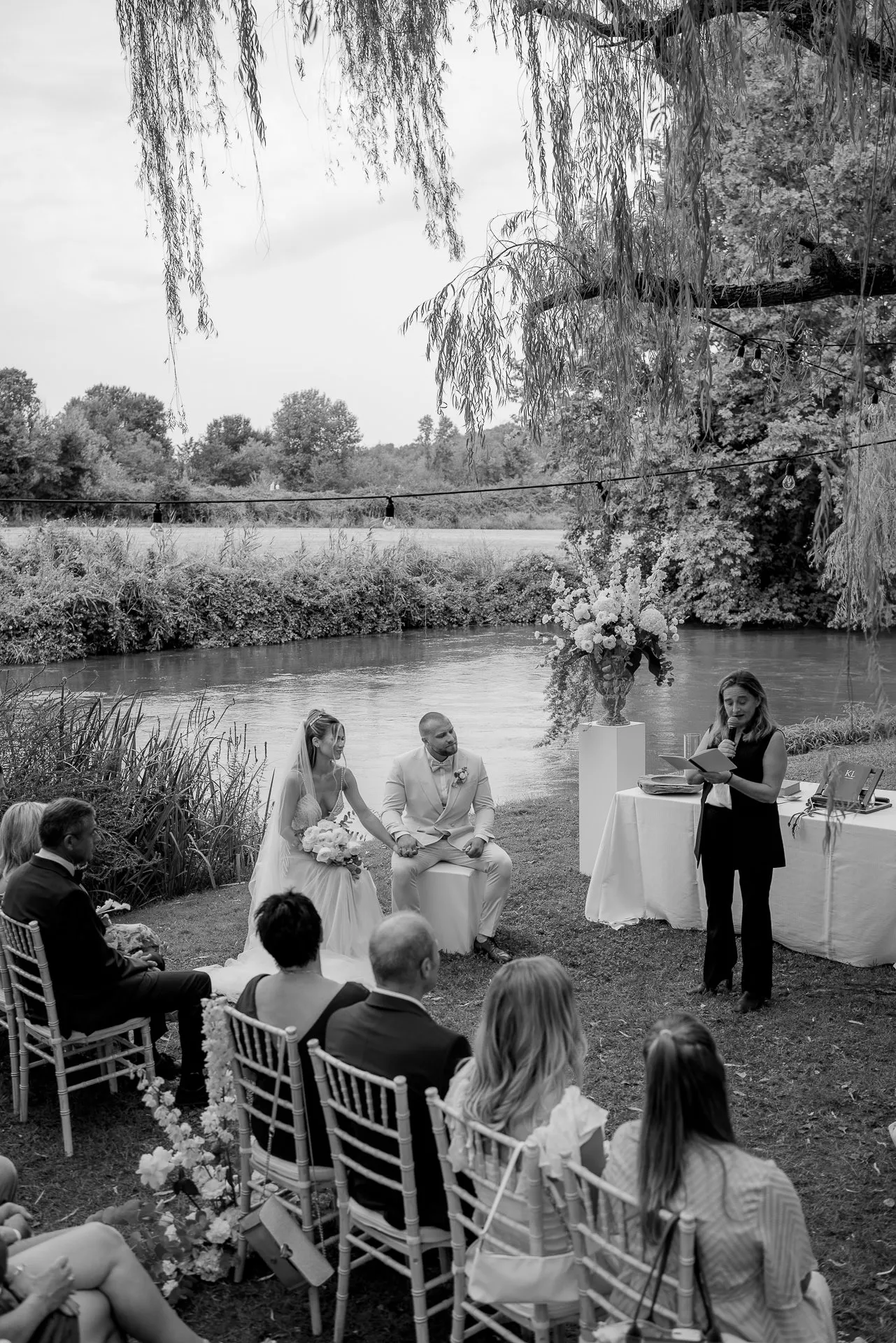 Intimate wedding ceremony by the picturesque riverside under weeping willows in Italy