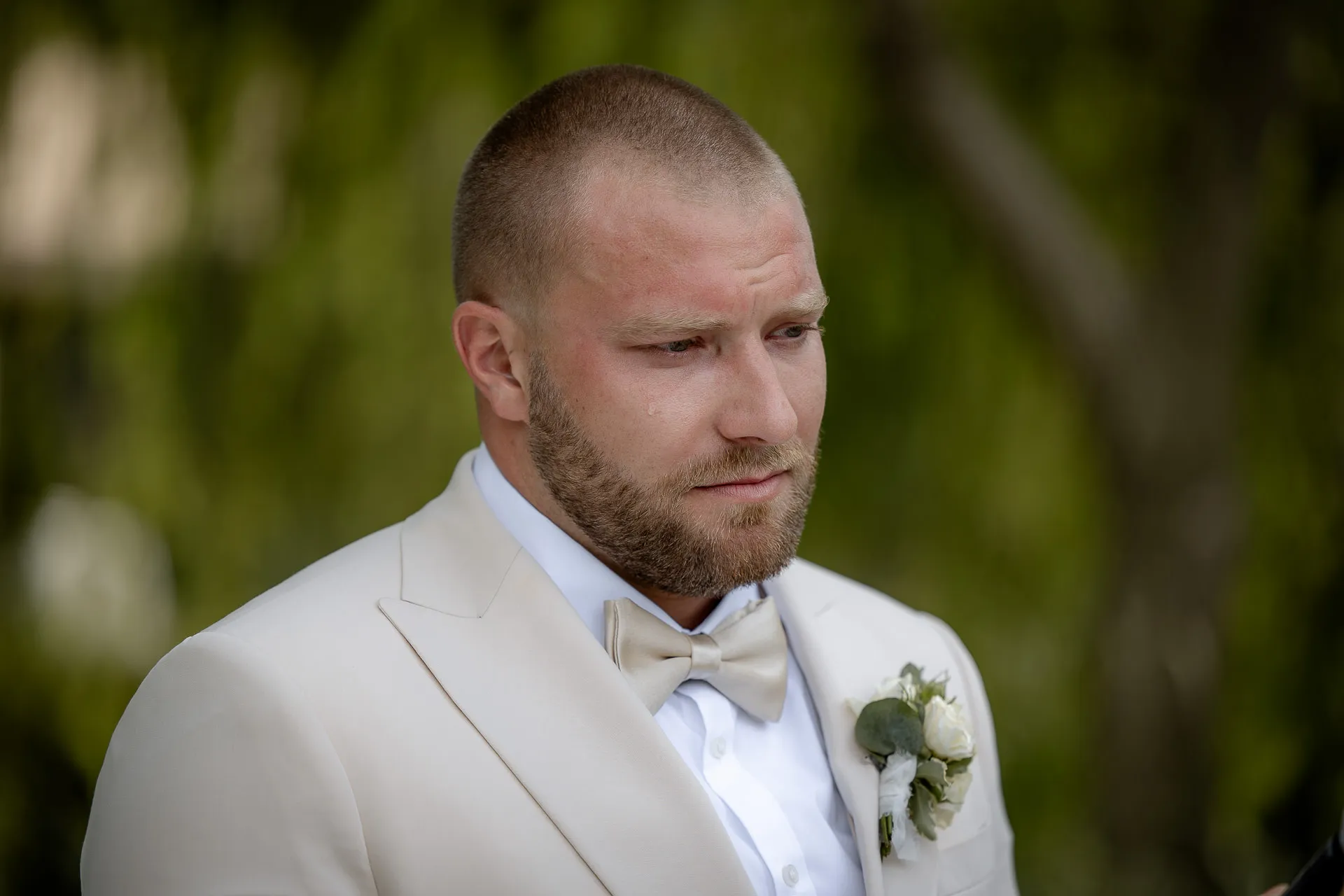 Emotional groom portrait in beige suit with boutonnière