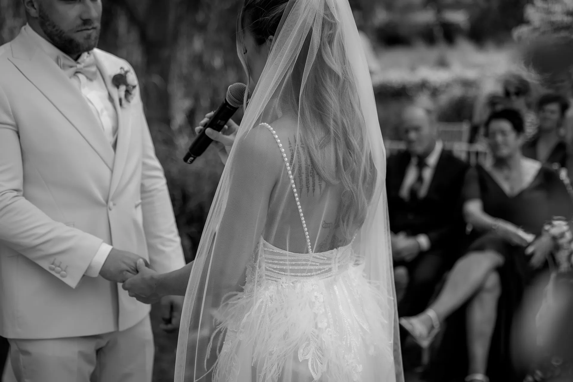Wedding couple holding hands during vows in black and white