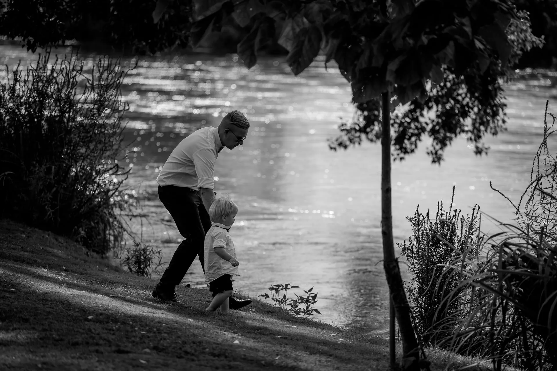 Grandmother and grandchild in tender moment by river during Italian wedding