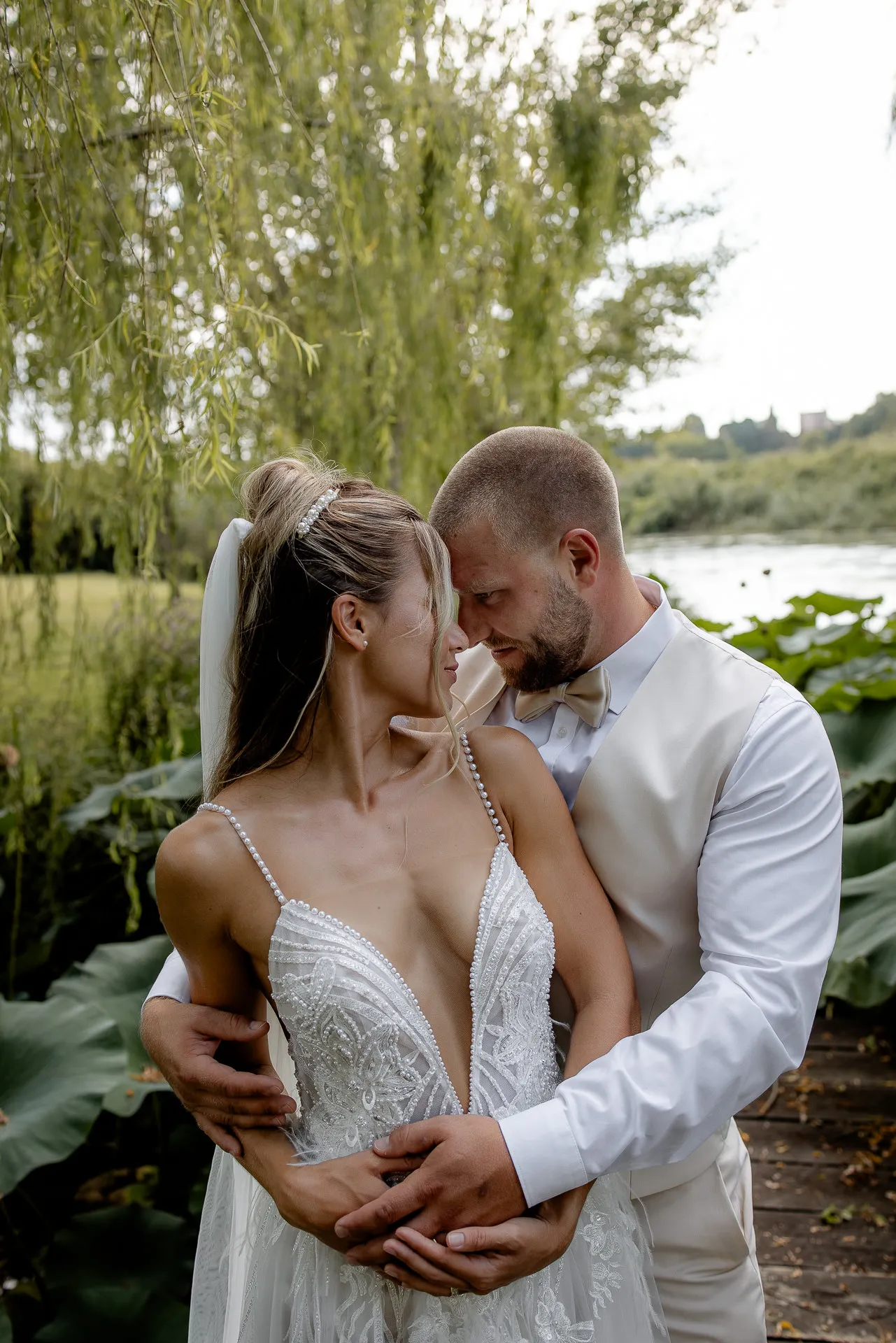 Intimate couple portrait by riverside with willow trees in Italy