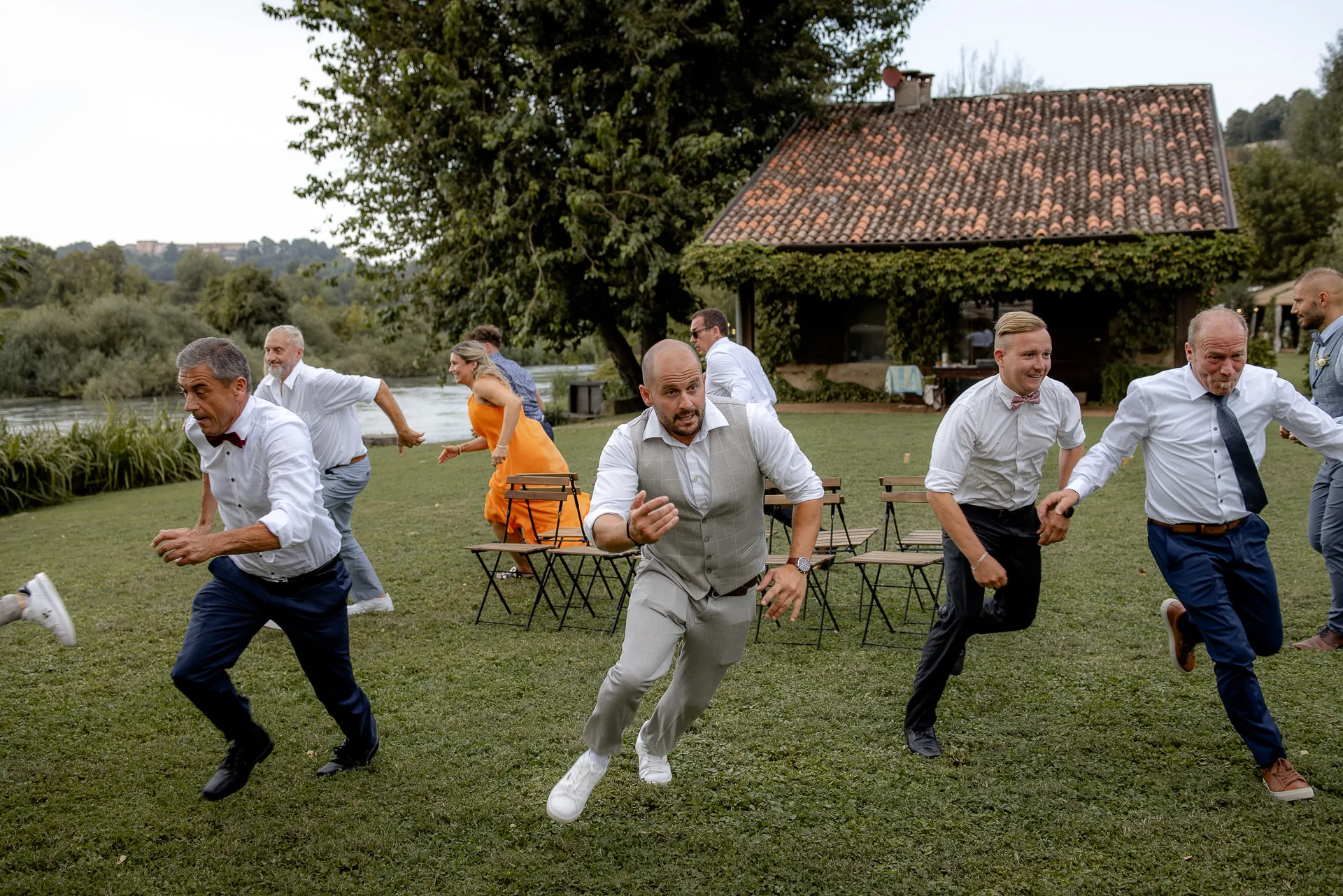 Male wedding guests dancing joyfully on lawn at La Finestra sul Fiume