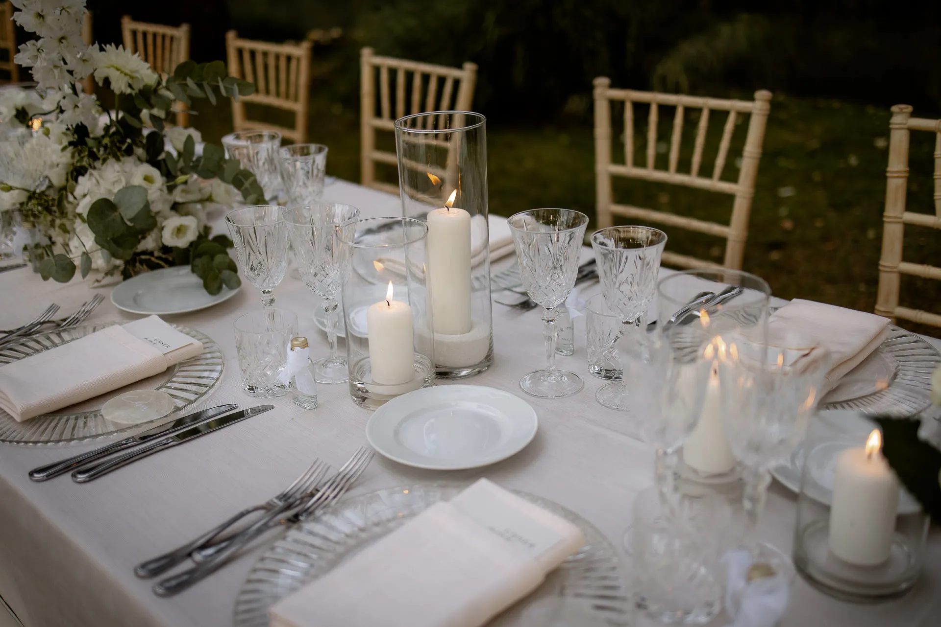 Elegant table setting with candles, crystal glasses and silver-rimmed plates