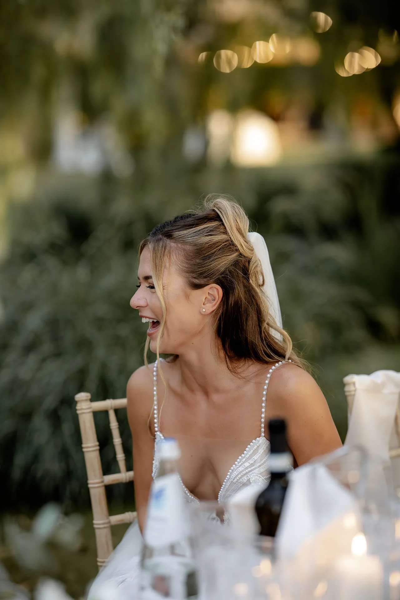 Laughing bride at evening reception with romantic bokeh lights background