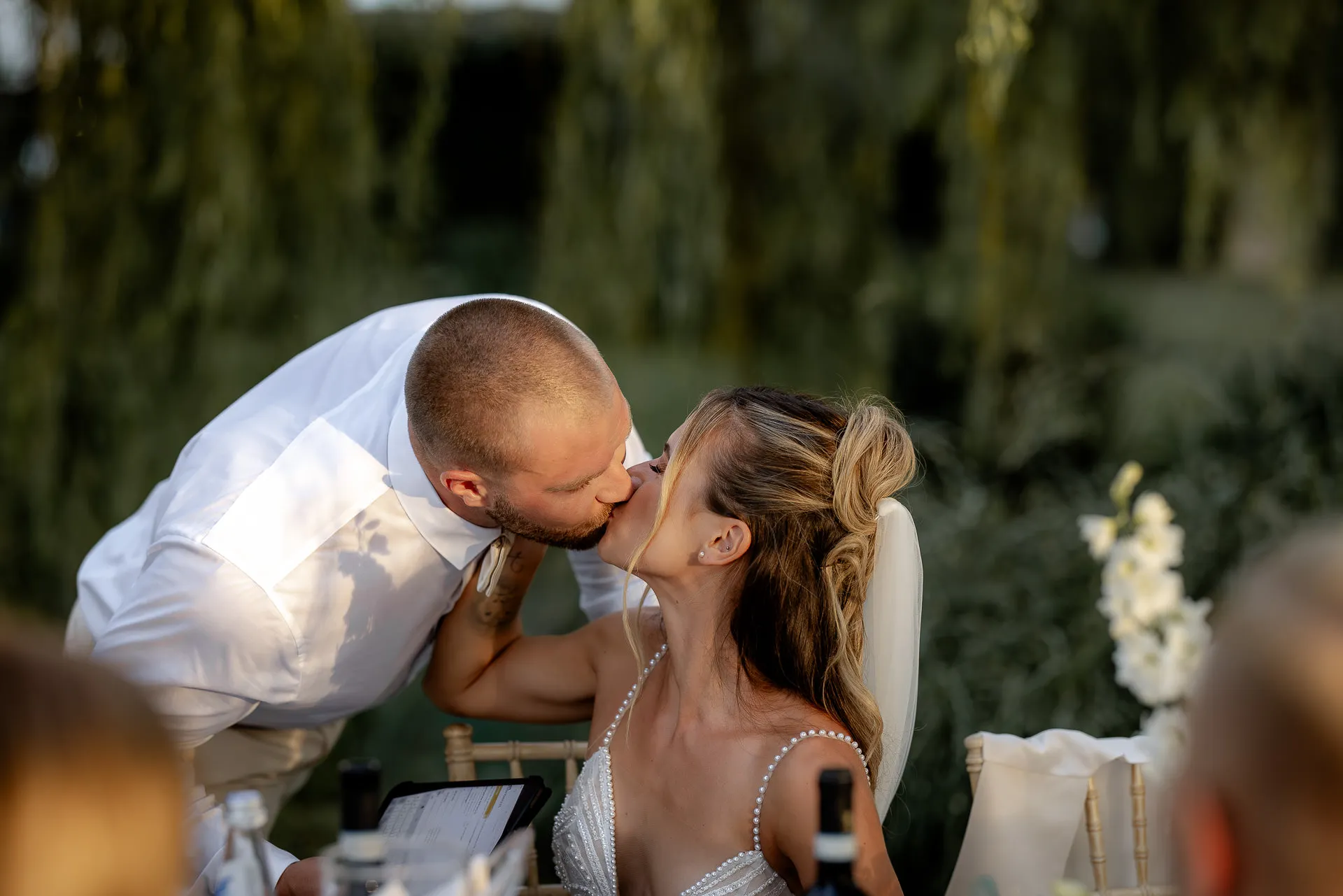 Bride and groom kissing romantically at wedding table during Italian reception