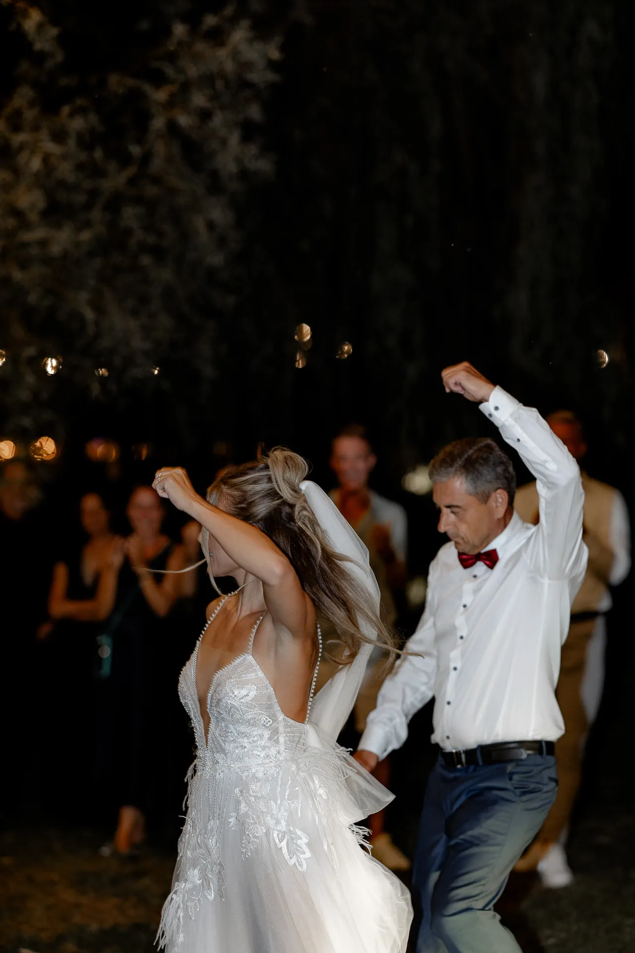 Bride dancing energetically with guest at nighttime outdoor wedding party