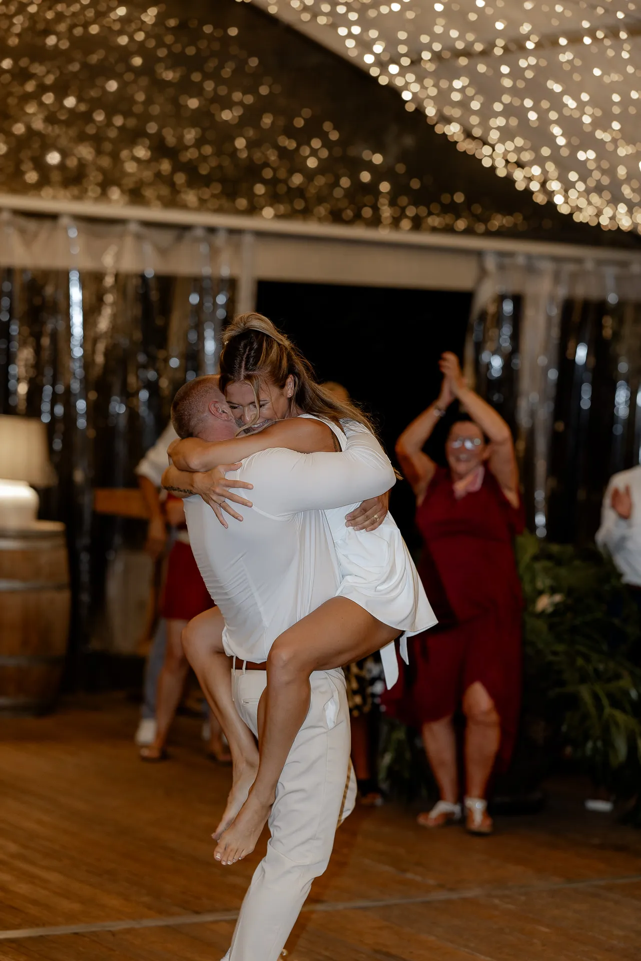 Intimate embrace of couple on dance floor under golden canopy of lights