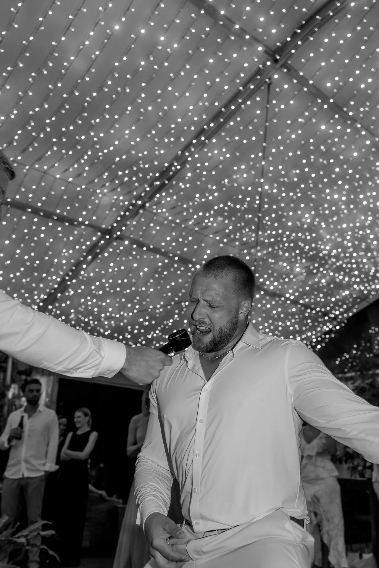 Groom dancing energetically under canopy of lights at Italian wedding party