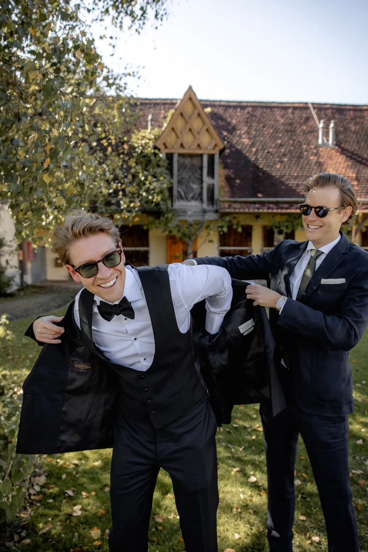 Groom with groomsman putting on jacket at Gut Sonnenhausen wedding