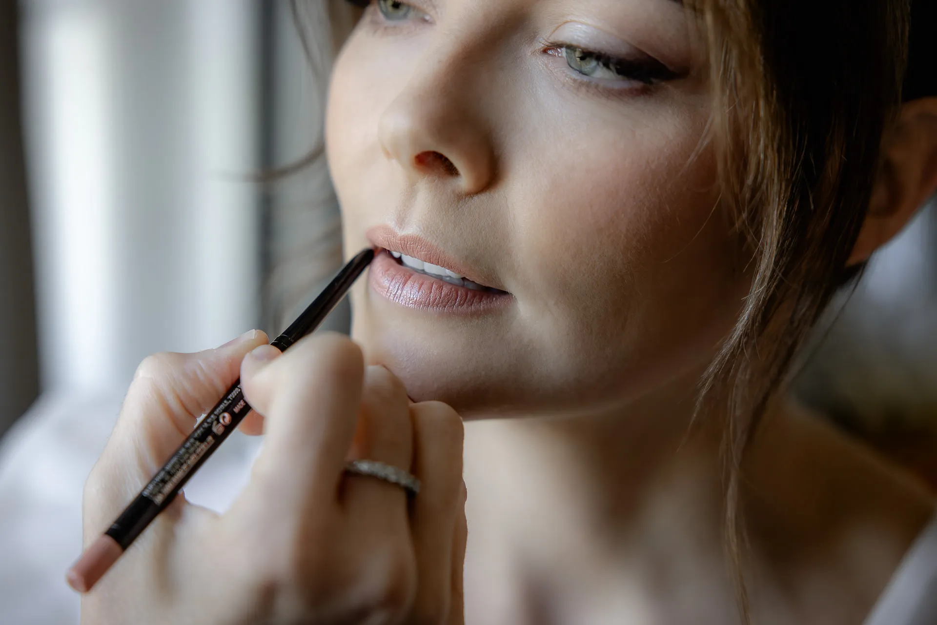 Bride applying lip liner during wedding preparation at Gut Sonnenhausen