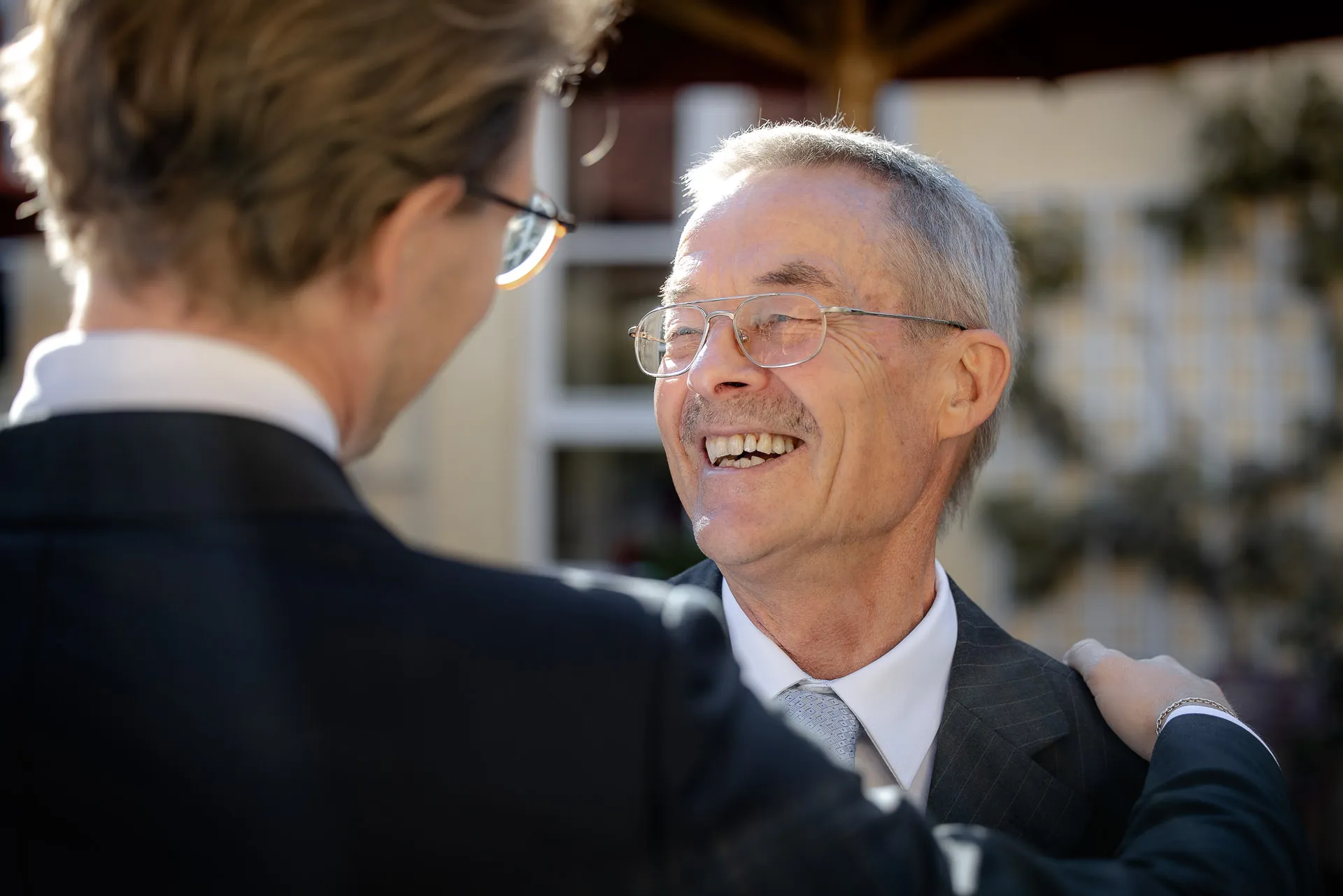Smiling grandfather in conversation at wedding celebration at Gut Sonnenhausen