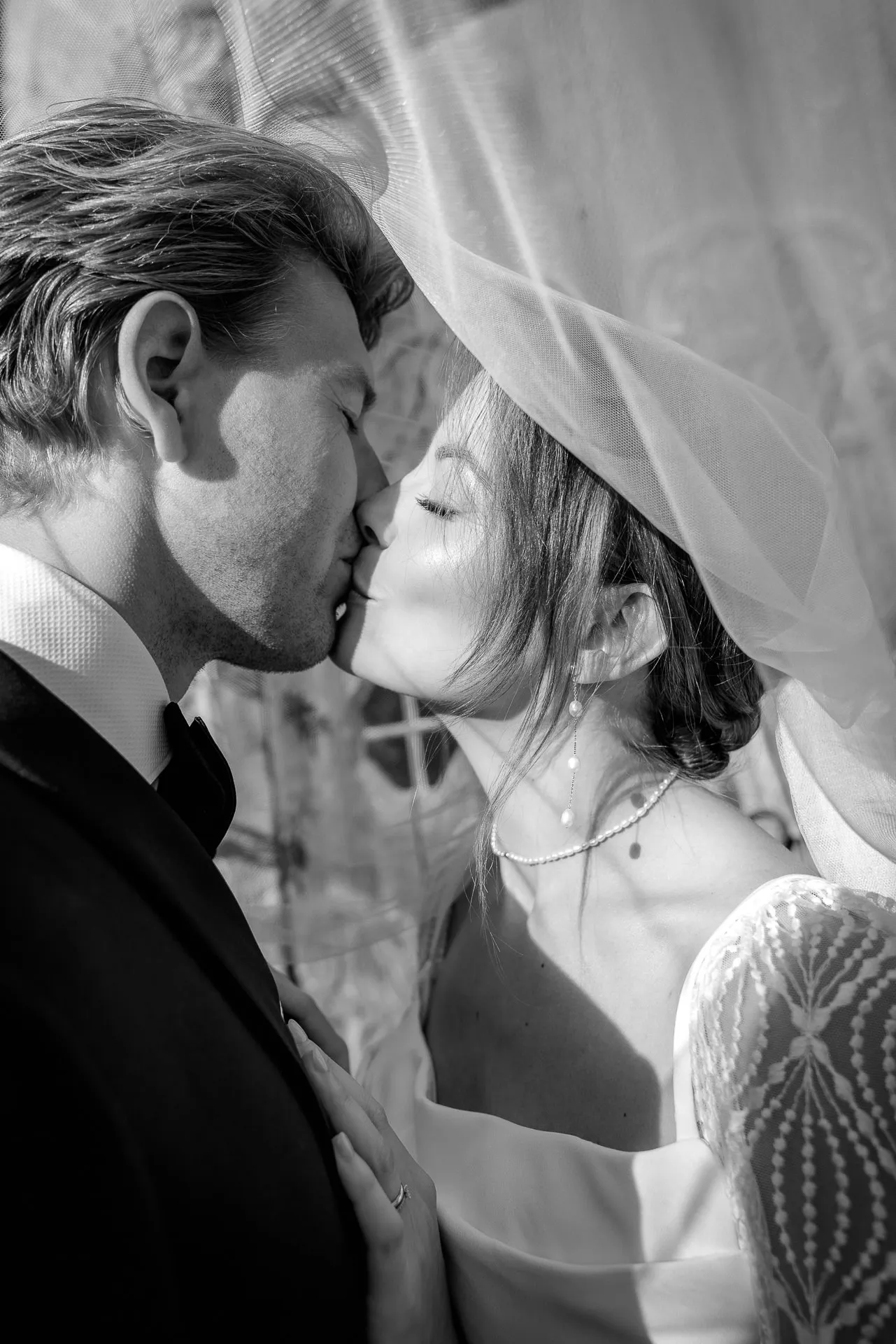 Bride and groom kissing intimately under veil at Gut Sonnenhausen wedding in black and white