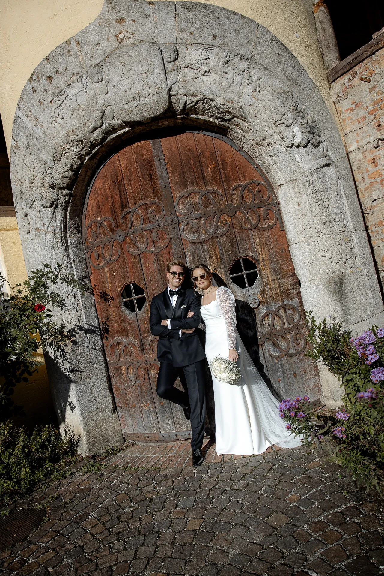 Bride and groom in front of historic wooden door with stone archway at Gut Sonnenhausen country wedding